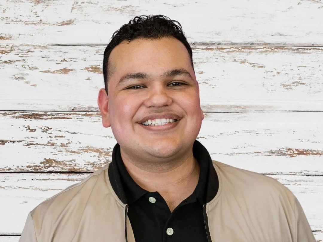 Eric Jimenez smiling in professional portrait against light wooden backdrop, representing Cocoon House team in Snohomish County