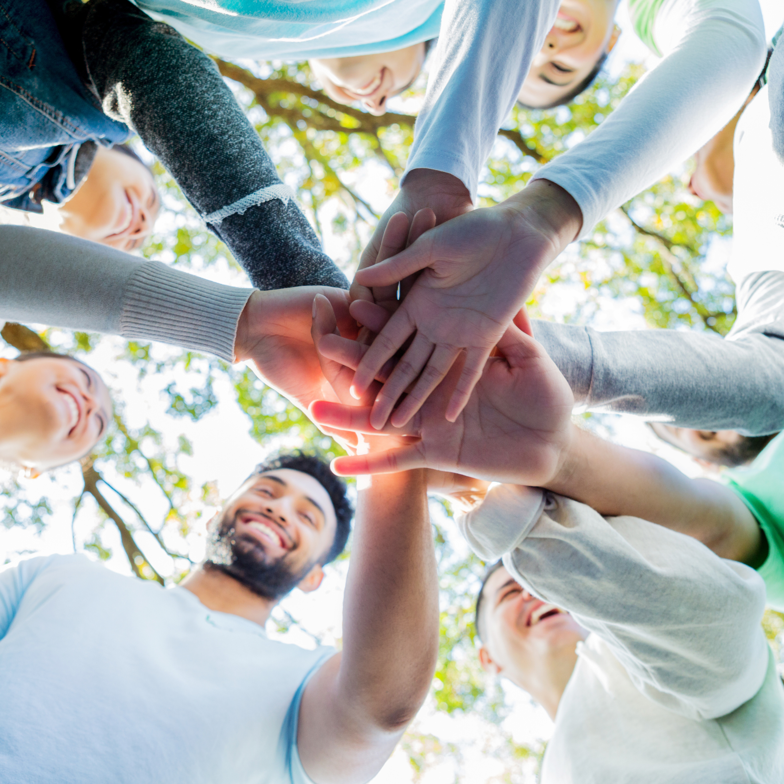 Diverse group of friends stacking hands together outdoors in Snohomish County, representing unity and youth community support