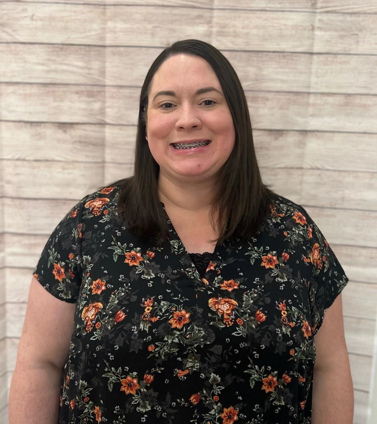 Tarah Wilder smiling in professional portrait against wooden backdrop, representing Cocoon House team in Snohomish County