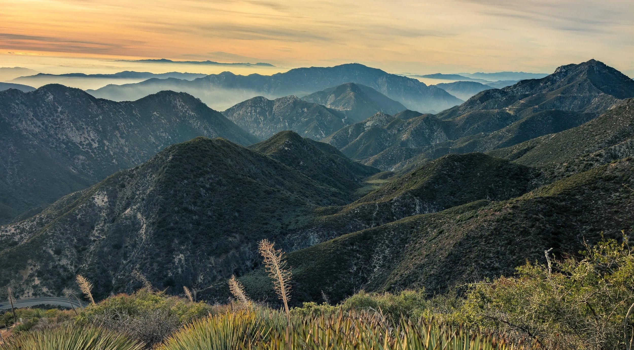 Los Angeles mountain range during sunset with layers of hills and clouds in the distance.