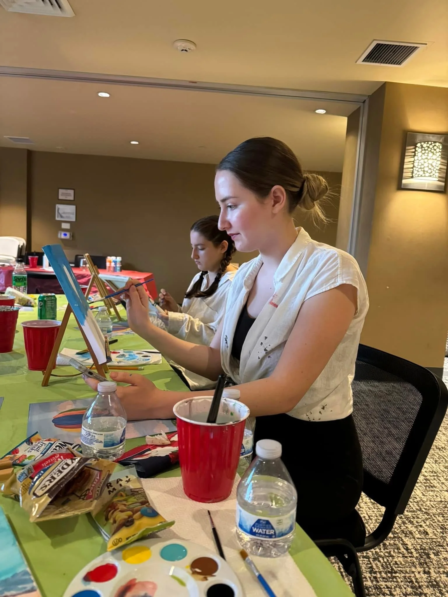 A woman painting on small canvases at a table.