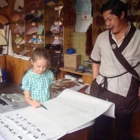 A young girl learning Chinese calligraphy.