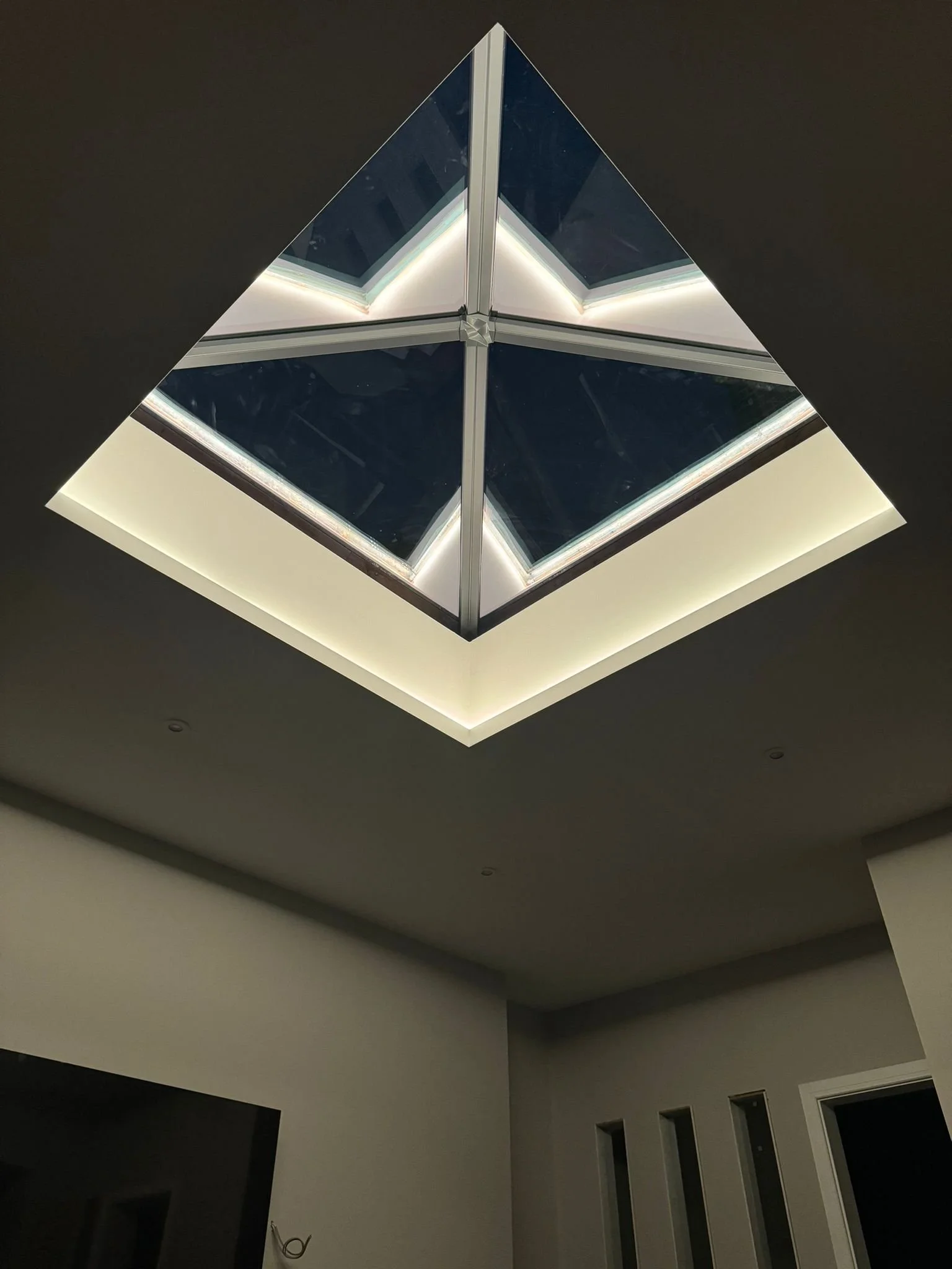 Modern ceiling light fixture with a geometric, layered design and bright LED lighting in a dark room.