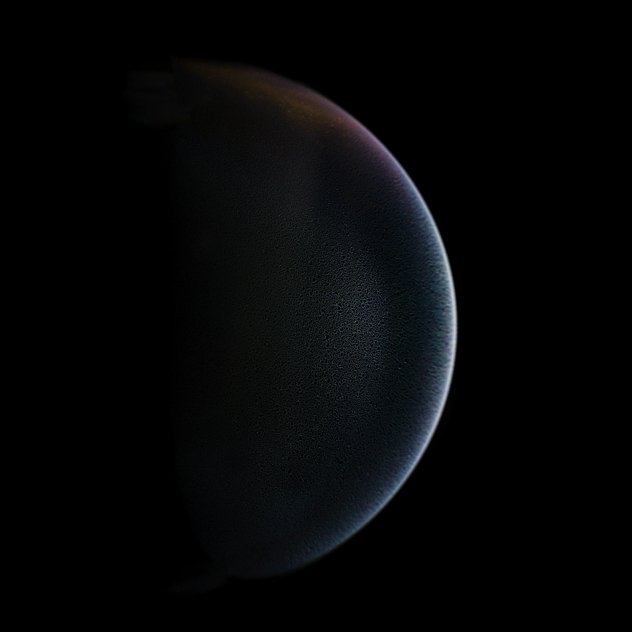 Close-up of a dark, textured surface with subtle purple and blue hues, against a black background.