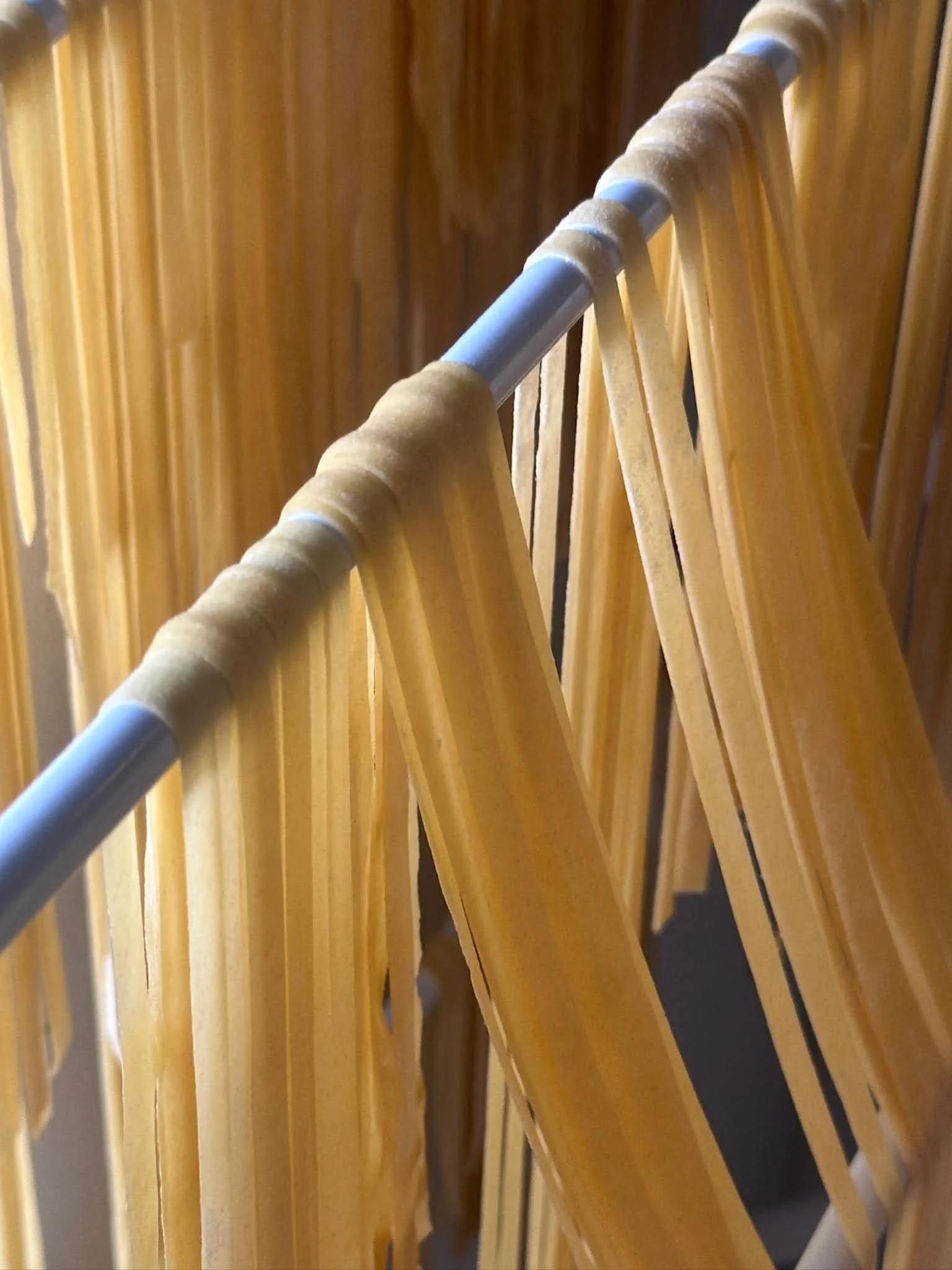 A wooden clothing rack with a white metal rod, holding a beige fabric strap or belt.