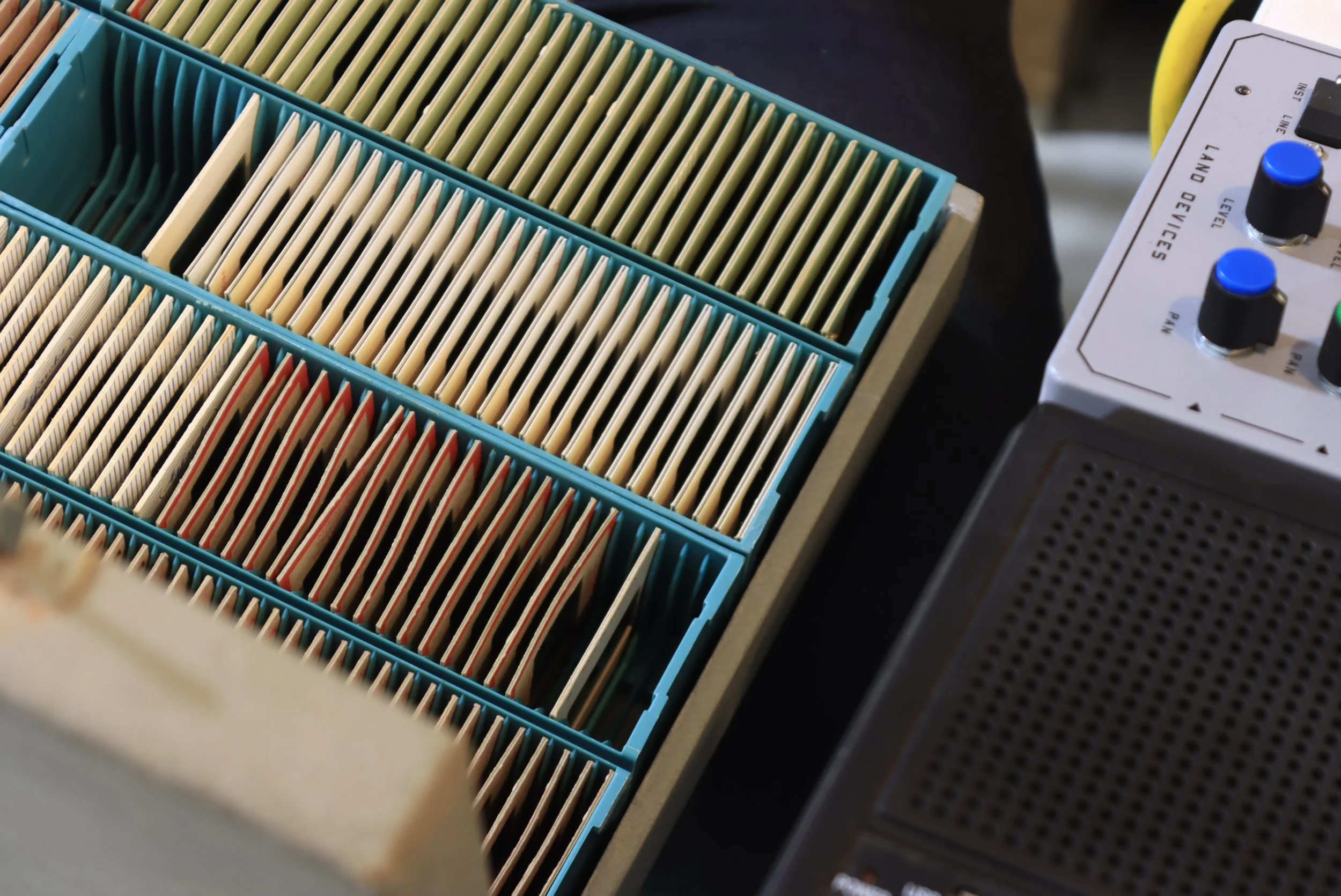 Multiple well-organized microplates used in laboratory experiments, with some colored red and others beige. Part of laboratory equipment is visible to the right, with knobs and labels indicating adjustable settings.