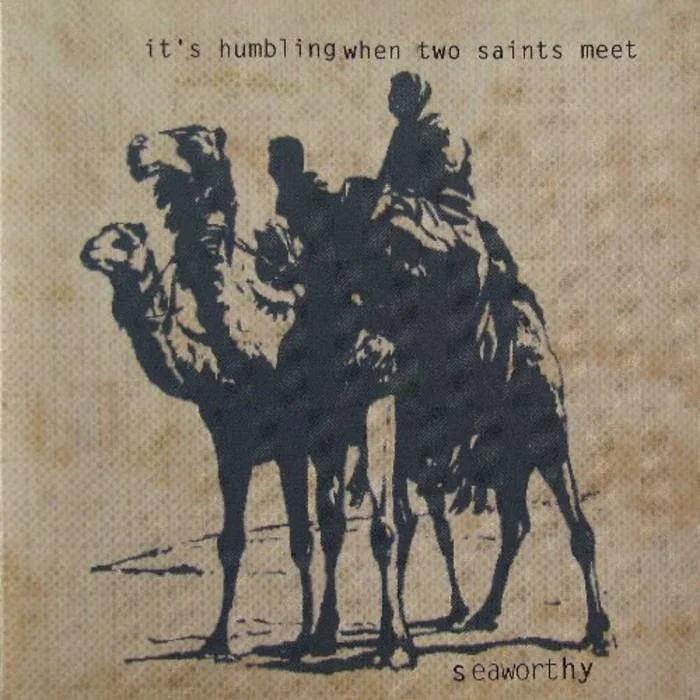 A silhouette sketch of two camels and a person riding the camel on a beige, textured background. The text above reads 'it’s humbling when two saints meet' and at the bottom right is the word 'seaworthy'.
