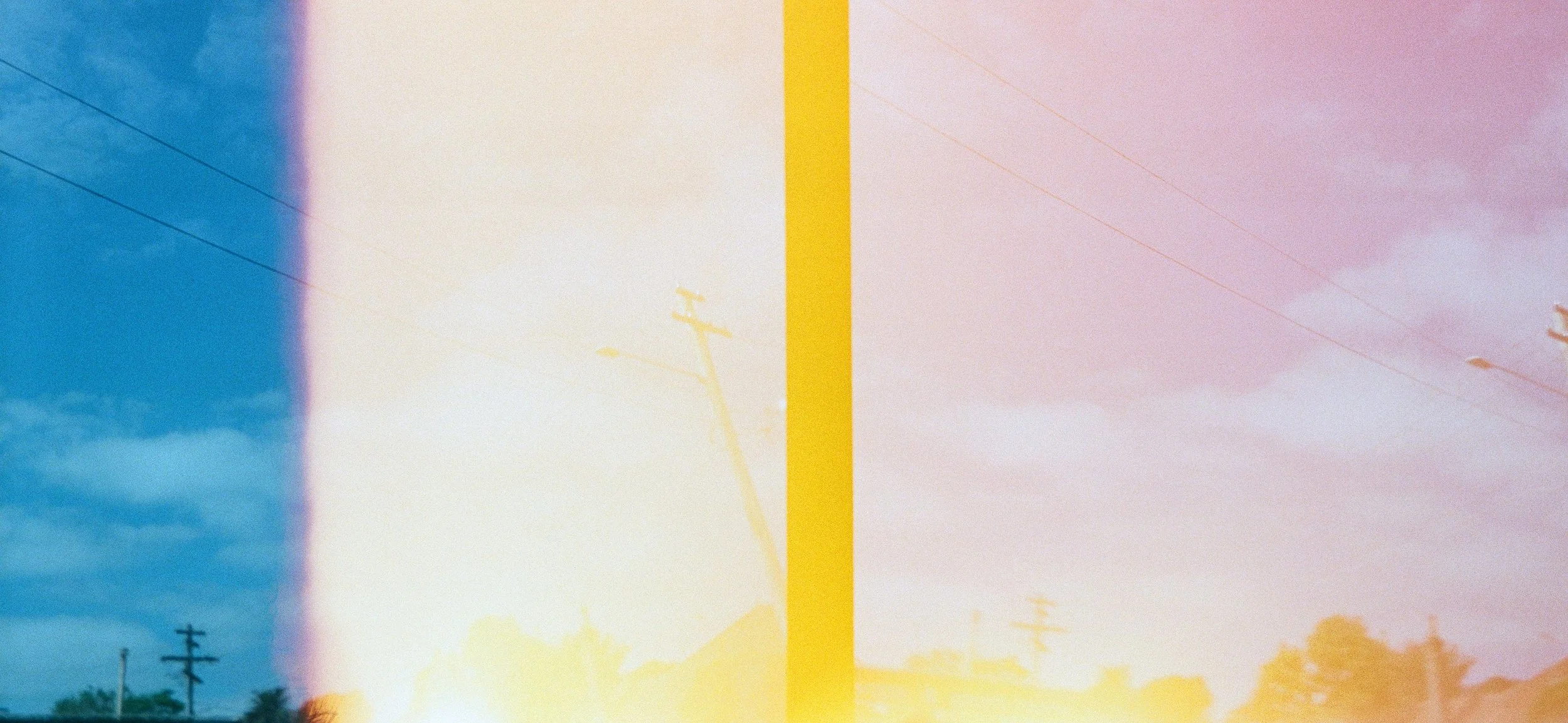 Half of the image shows a blue sky with clouds and power lines, while the other half has a pink hue with similar power lines and clouds, separated by a bright yellow vertical line in the center.