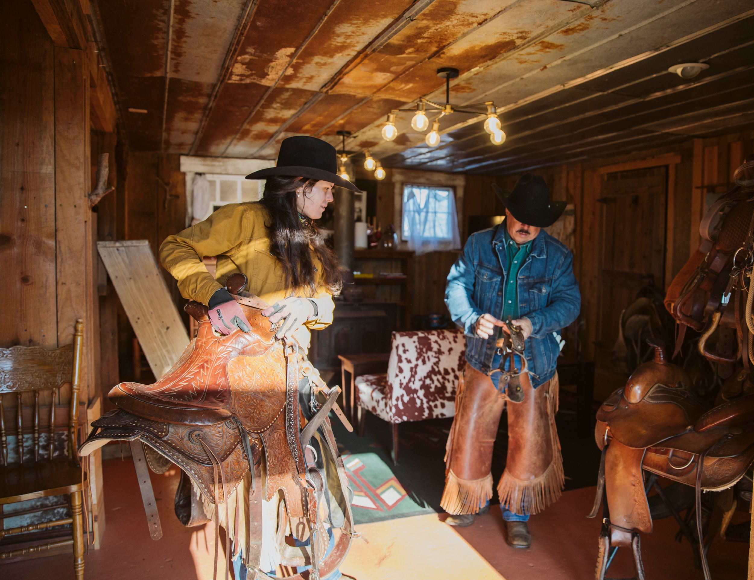 Ranch hands preparing saddles inside a tack room at a North Georgia ranch