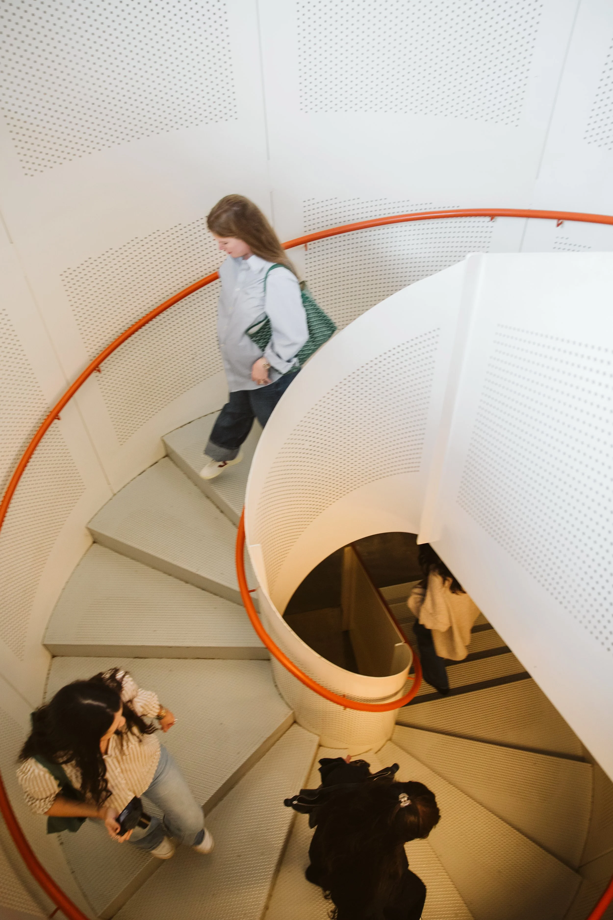 Resident walking down modern spiral staircase in apartment building