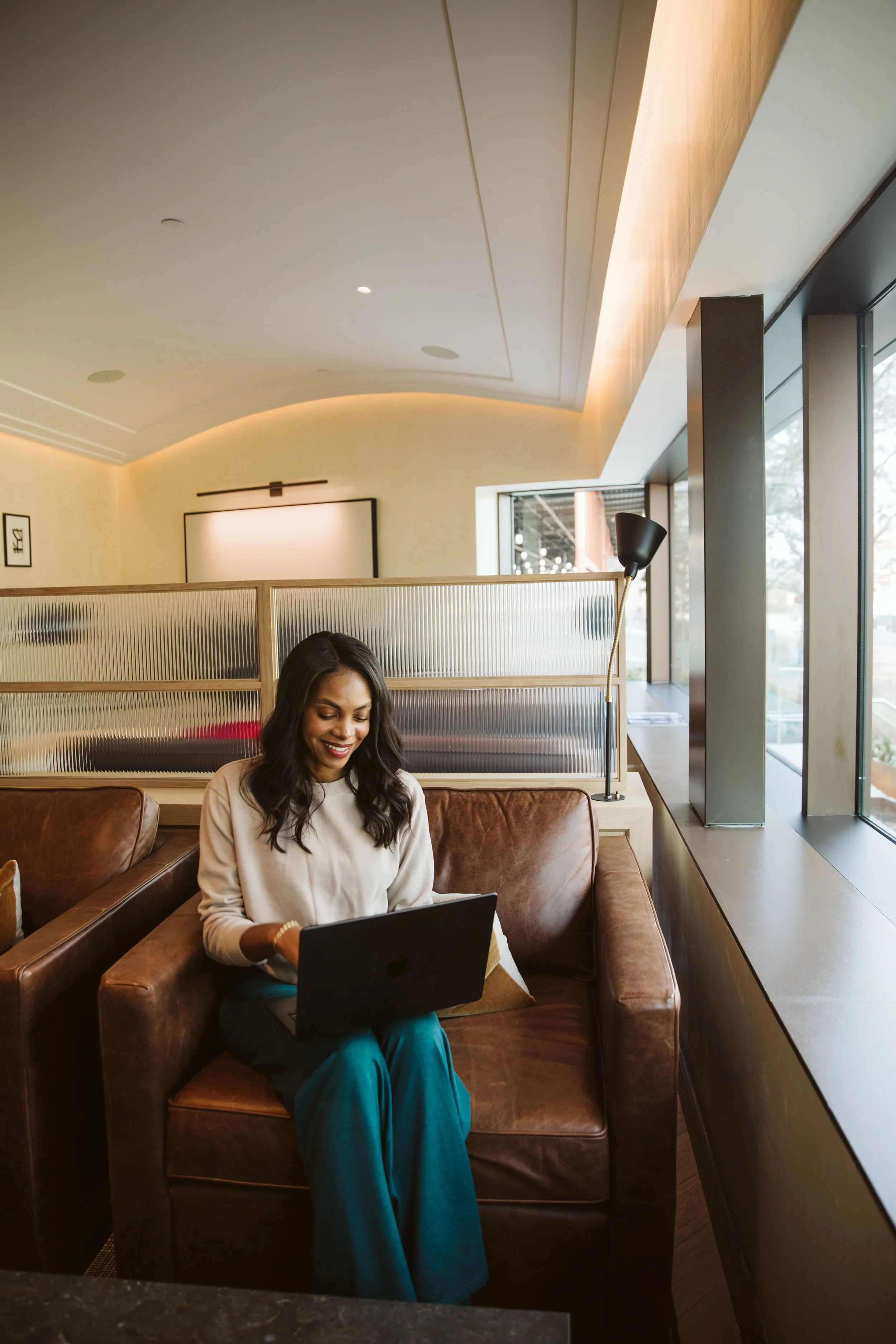 Woman working remotely on laptop in modern apartment lounge