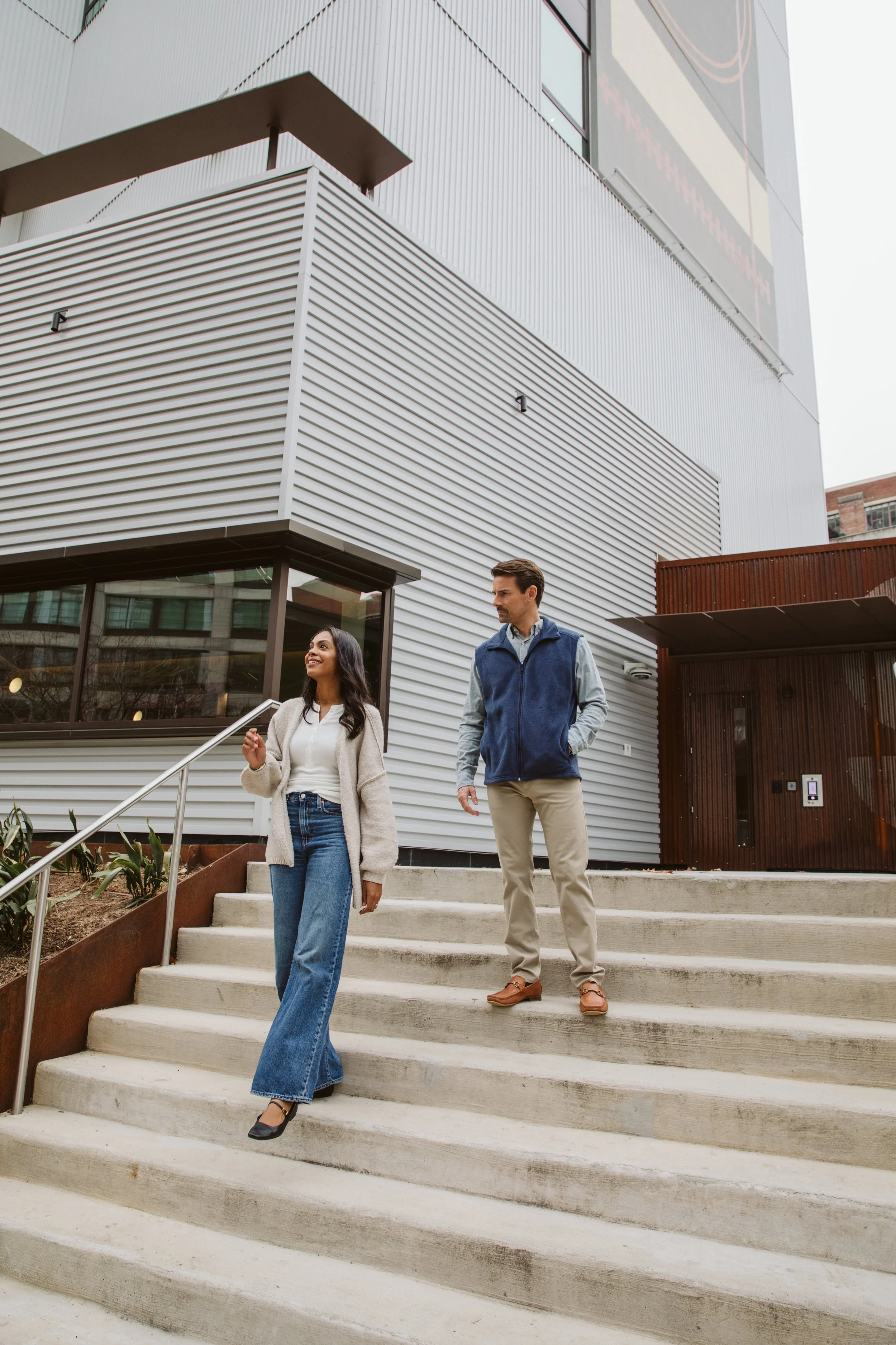 Couple walking down modern apartment building stairs