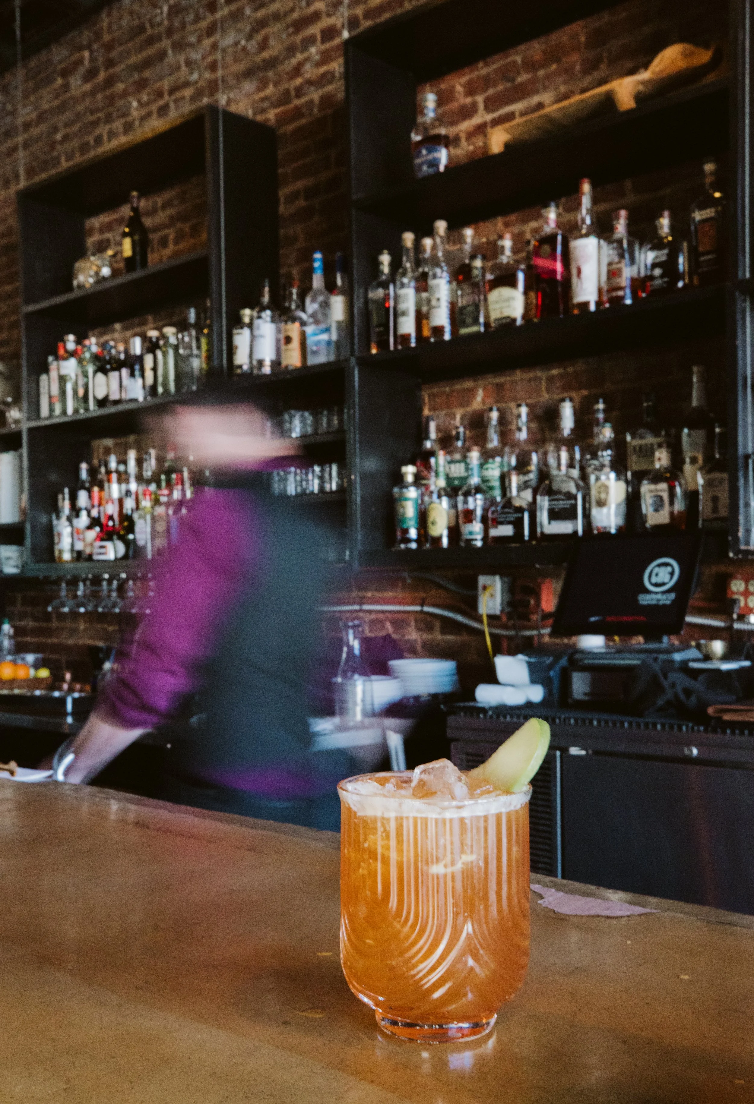 Cocktail on bar counter with bottles in background