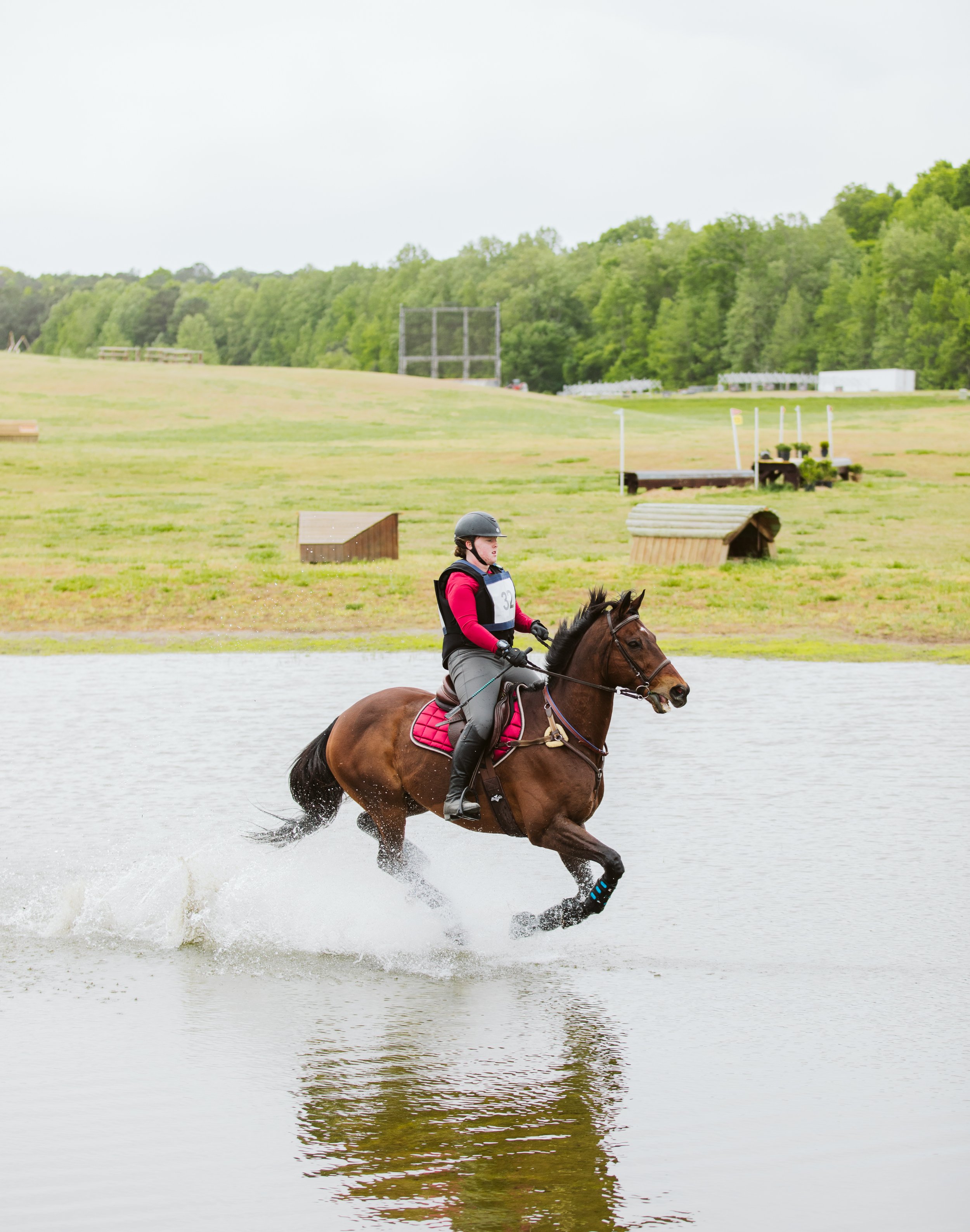 Horse galloping through water at horse trials