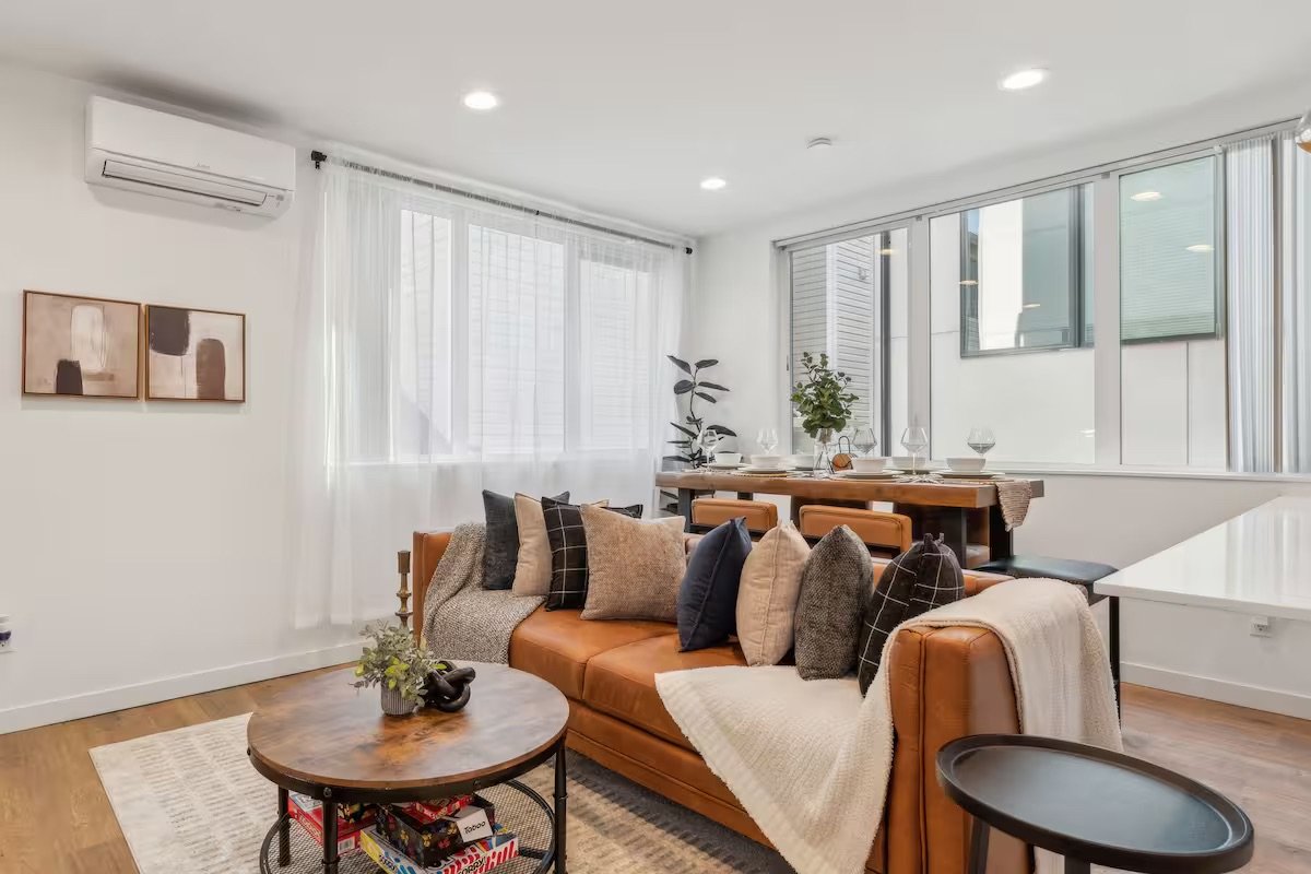 mid century modern designed living room with a leather couch, lots of comfy pillows, a blanket, and art