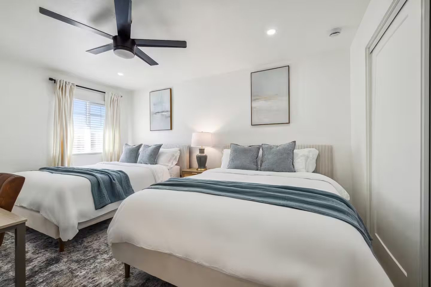 ocean themed bedroom with two full-size beds and a work desk