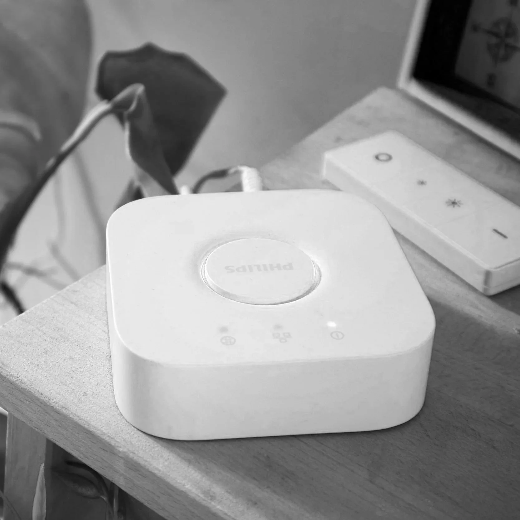 A white Philips sleep apnea CPAP machine on a wooden surface next to a remote control with sleep mode icons.