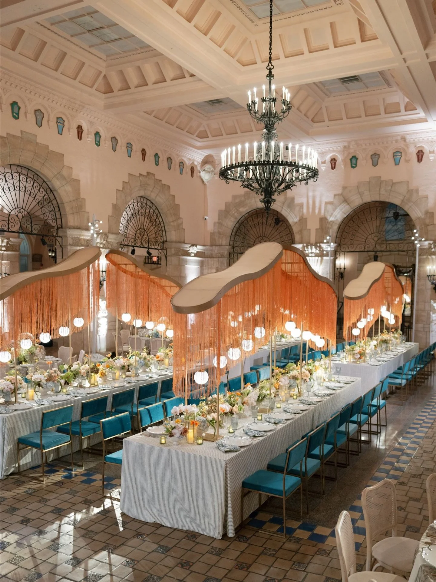 Emma &amp; Will&rsquo;s wedding dinner unfolded beneath the gilded halls of the Flagler Museum, anchored by four statement tables that set the tone for the evening. Copper fringe shimmered overhead as velvet chairs and textured linens framed lush flo
