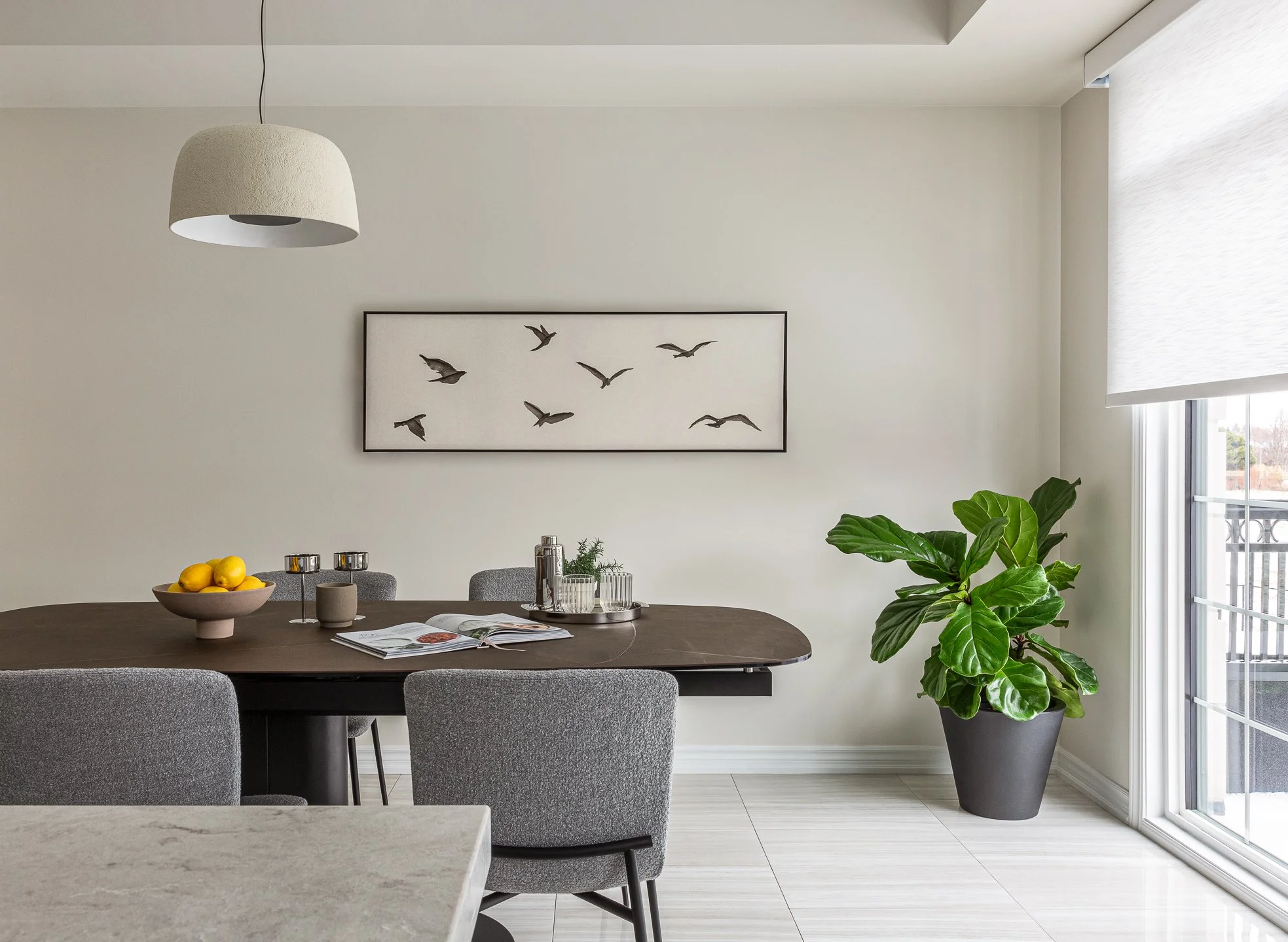A modern dining room with a plaster pendant light, luxury dining room furniture and nature art.