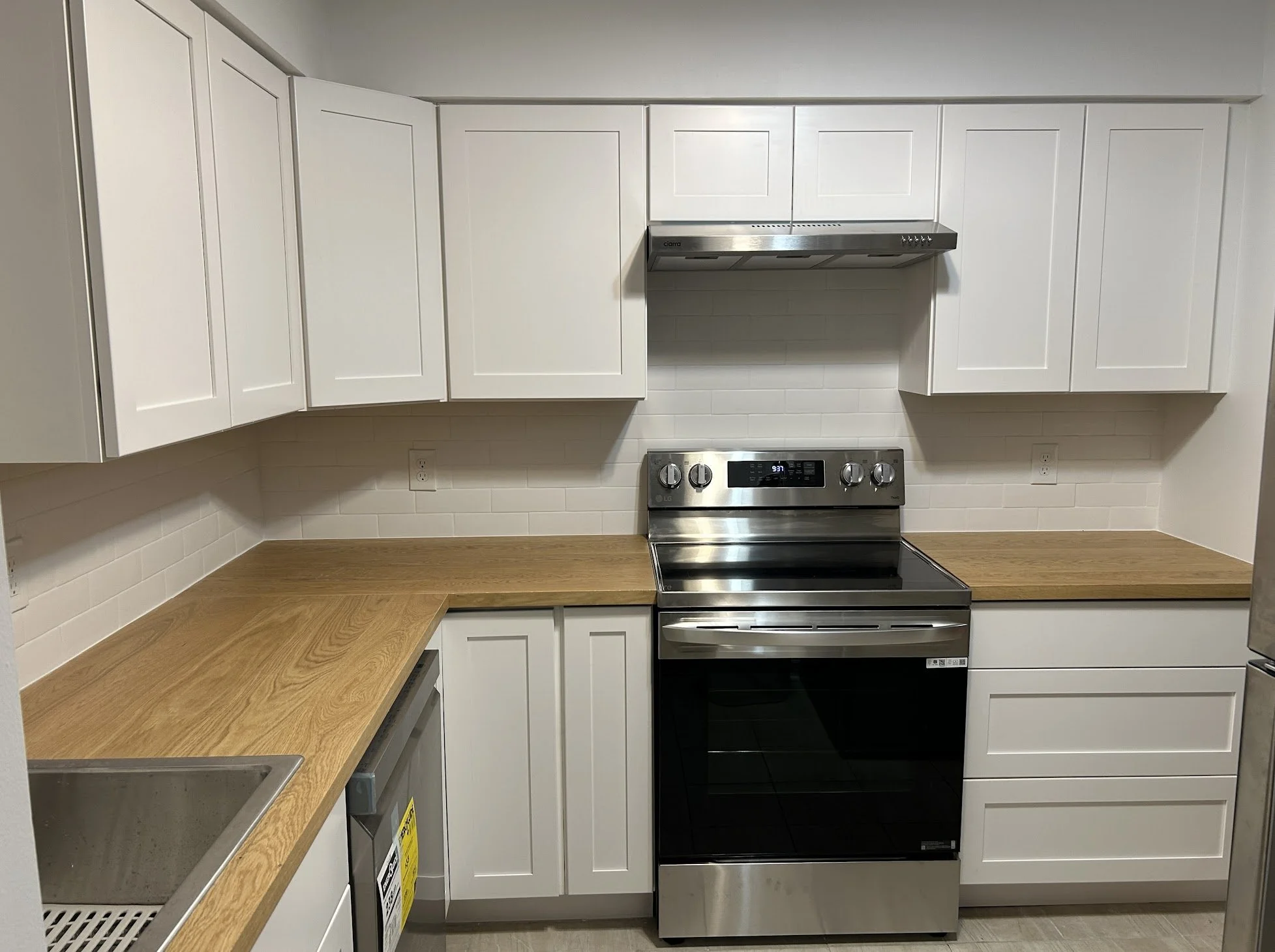Modern kitchen with white cabinets, wooden countertops, stainless steel stove, and white subway tile backsplash.