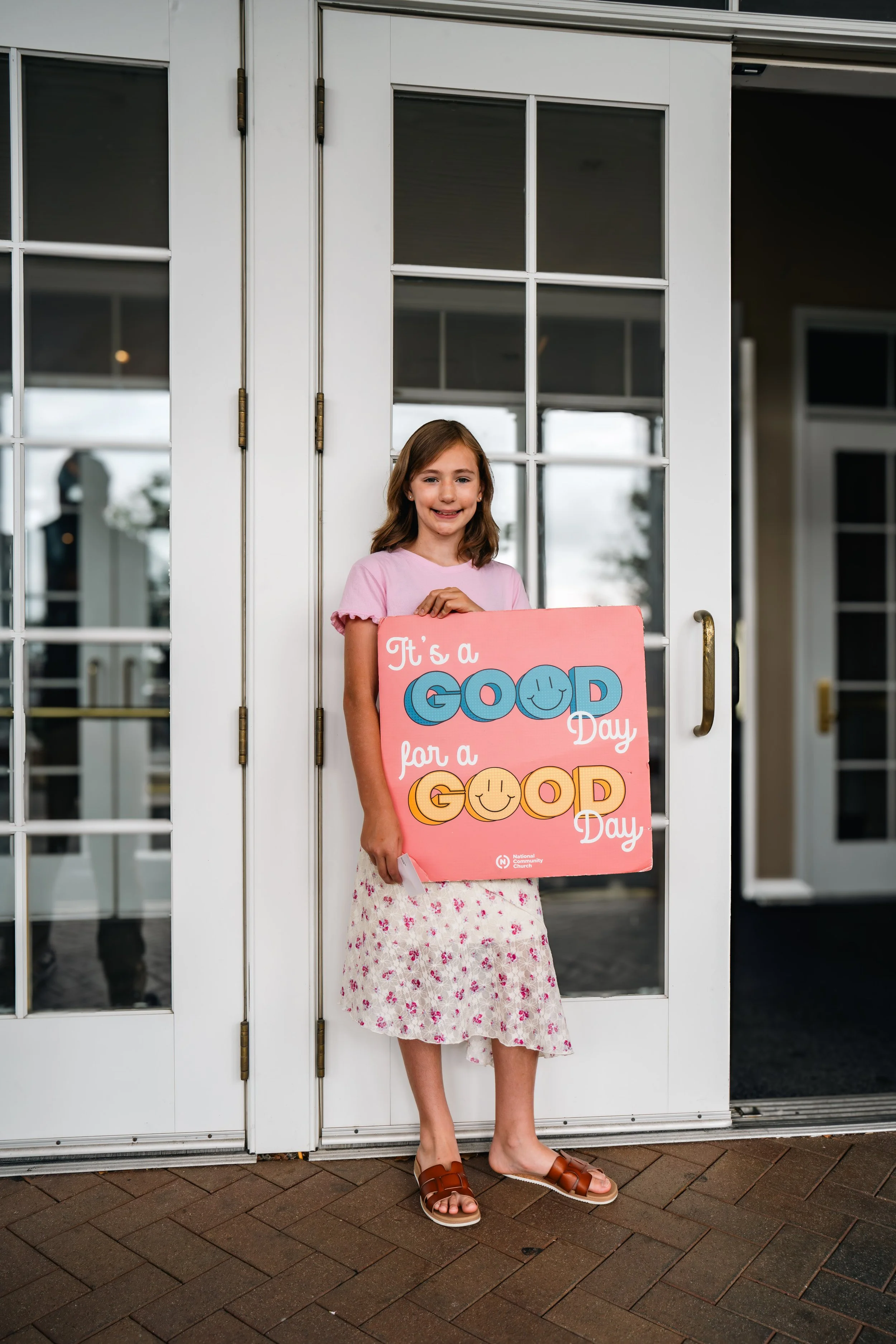 A young boy with face paint resembling a puppy, smiling and looking at a phone, with an adult woman nearby in a blurred background.