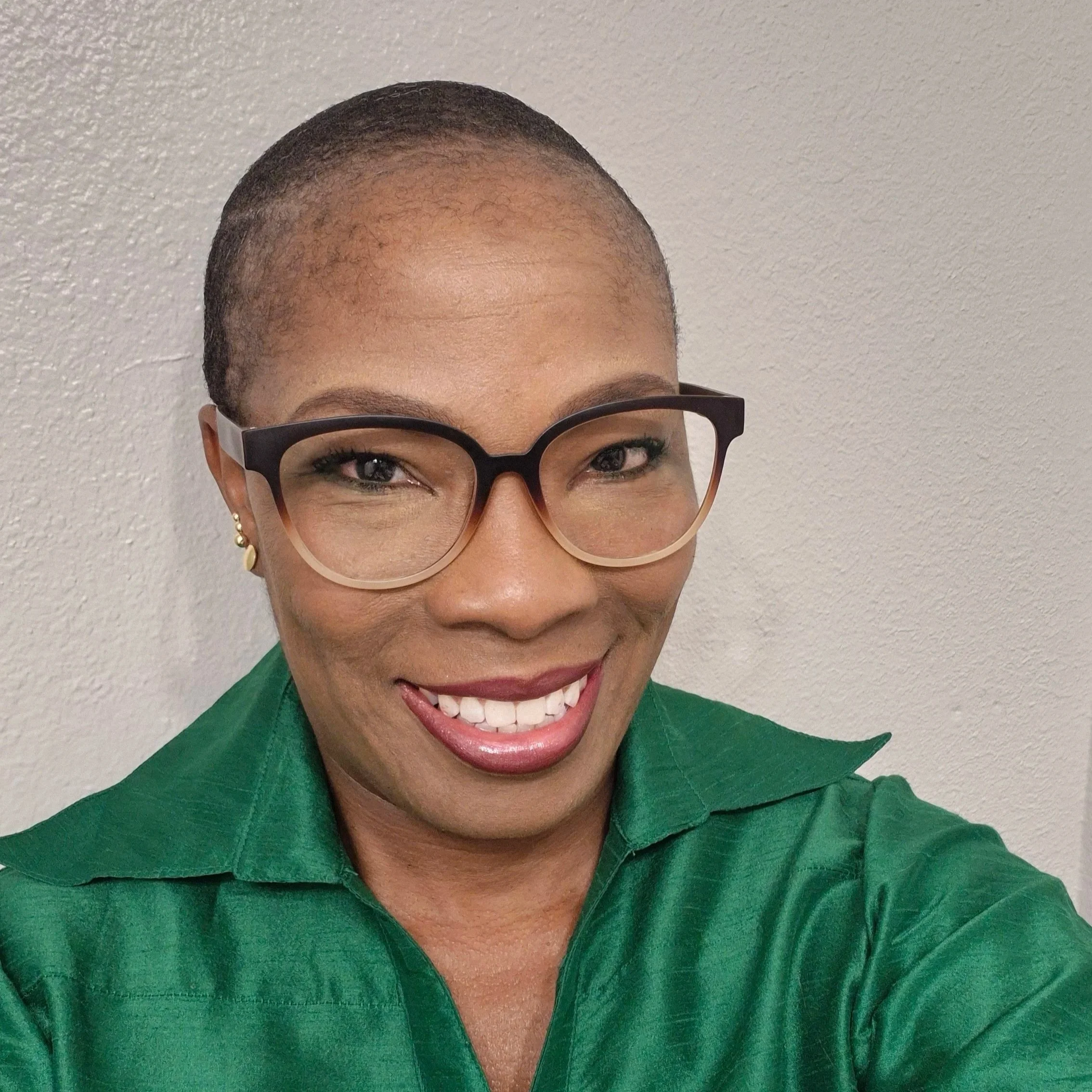 Smiling woman in dark brimmed glasses and a green button up shirt.