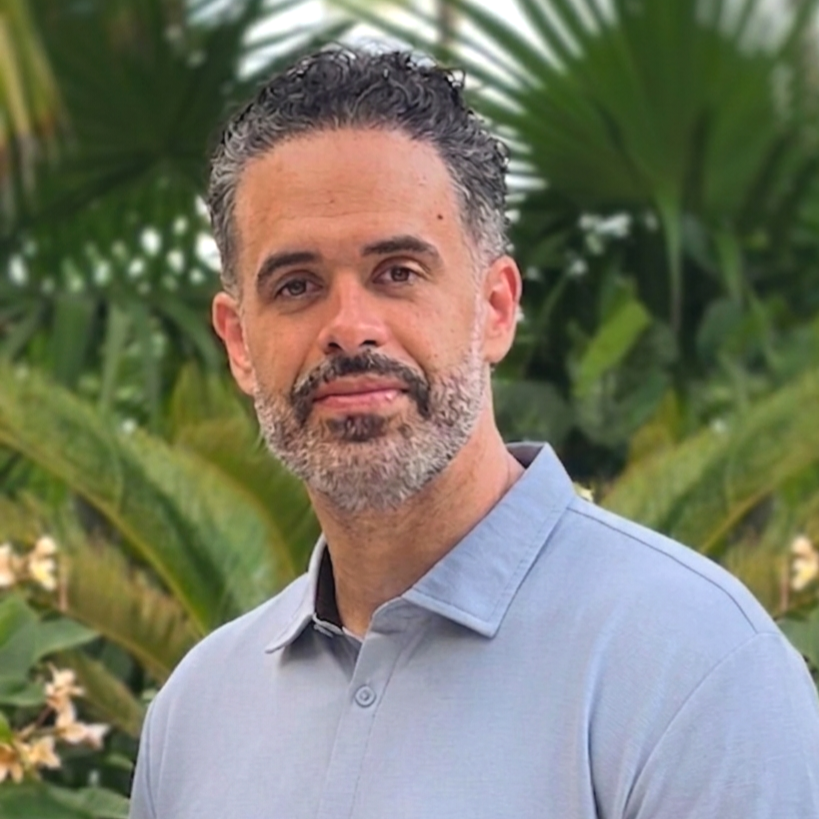 A man with beard with tropical plants in background