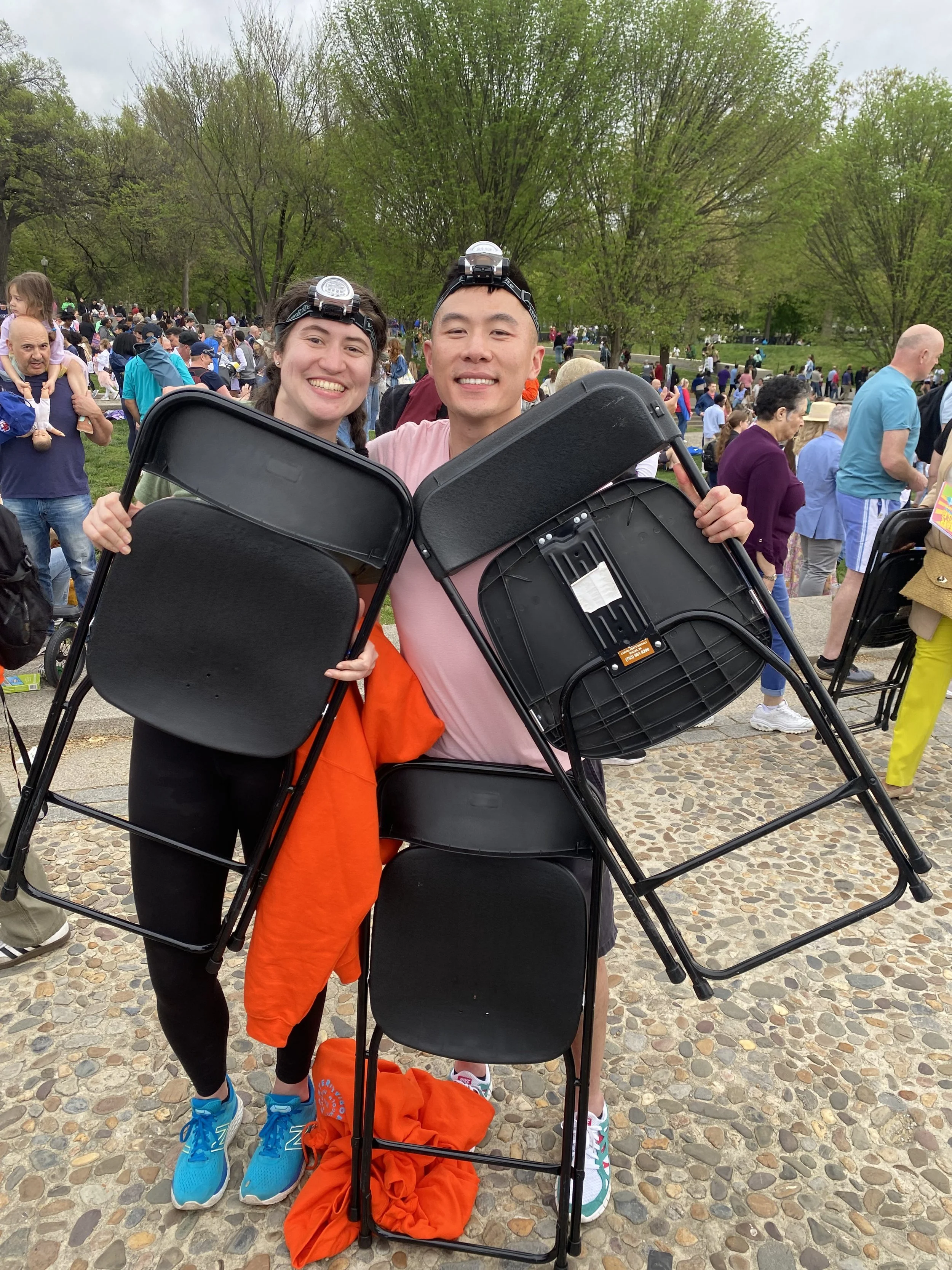 Two friends sitting on the floor, smiling and laughing, in front of a curtain.