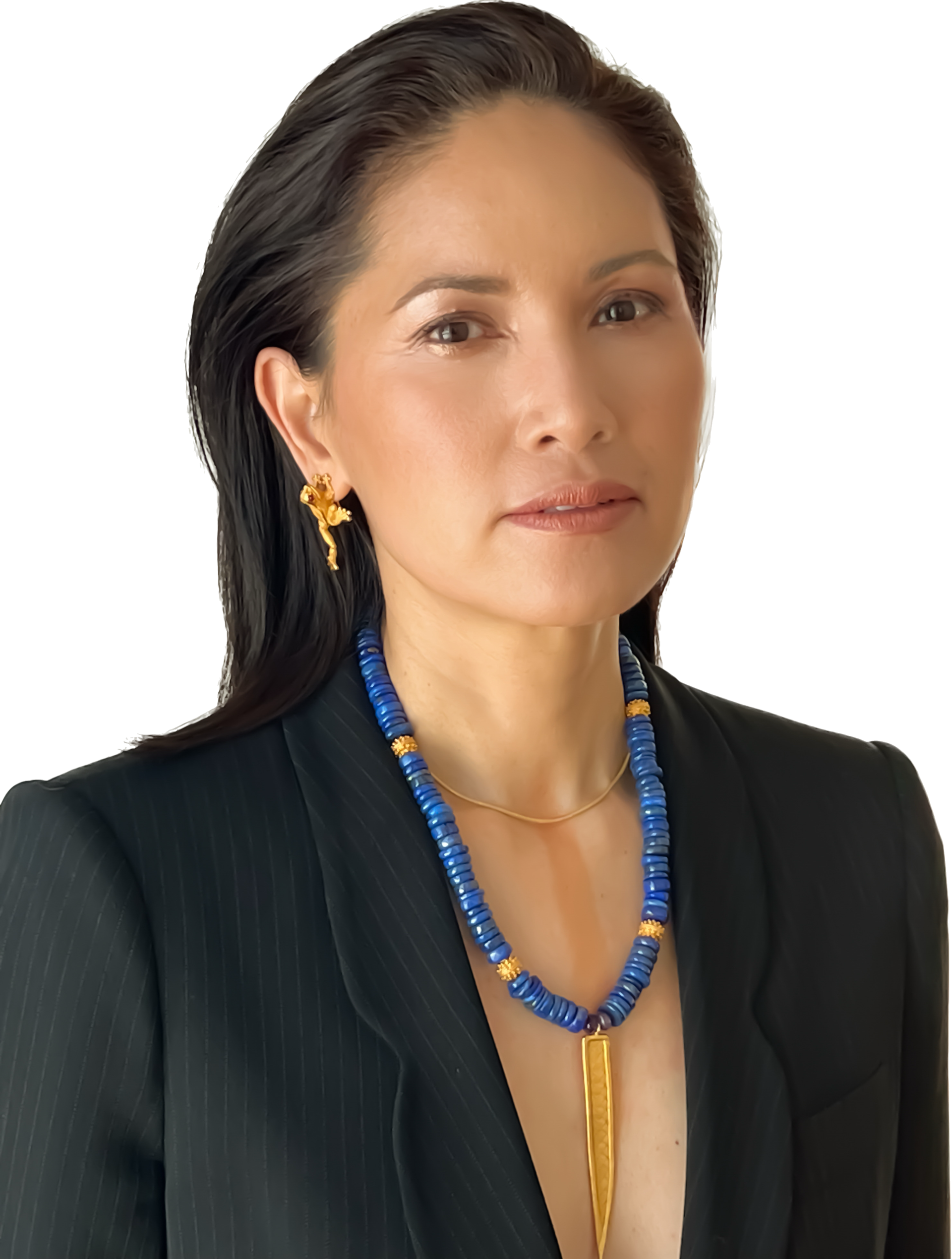 A woman with dark hair wearing a black blazer, gold earrings, a blue beaded necklace with gold accents, and a gold pendant necklace.