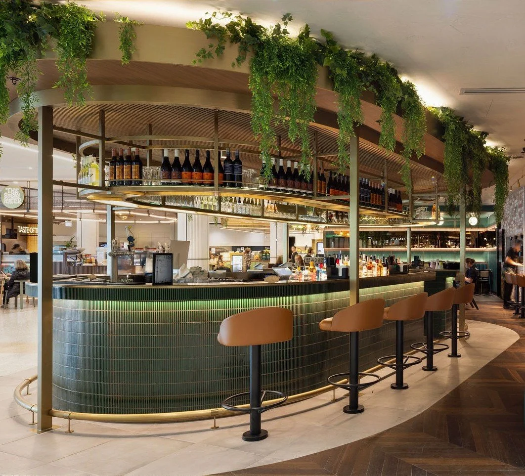 Interior view of a restaurant called Lotus Dumpling Bar with modern decor, green accents, and seating areas including chairs and booths.