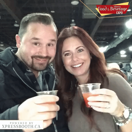 A man and woman smiling and holding drinks at the Alberta Food & Beverage Expo.