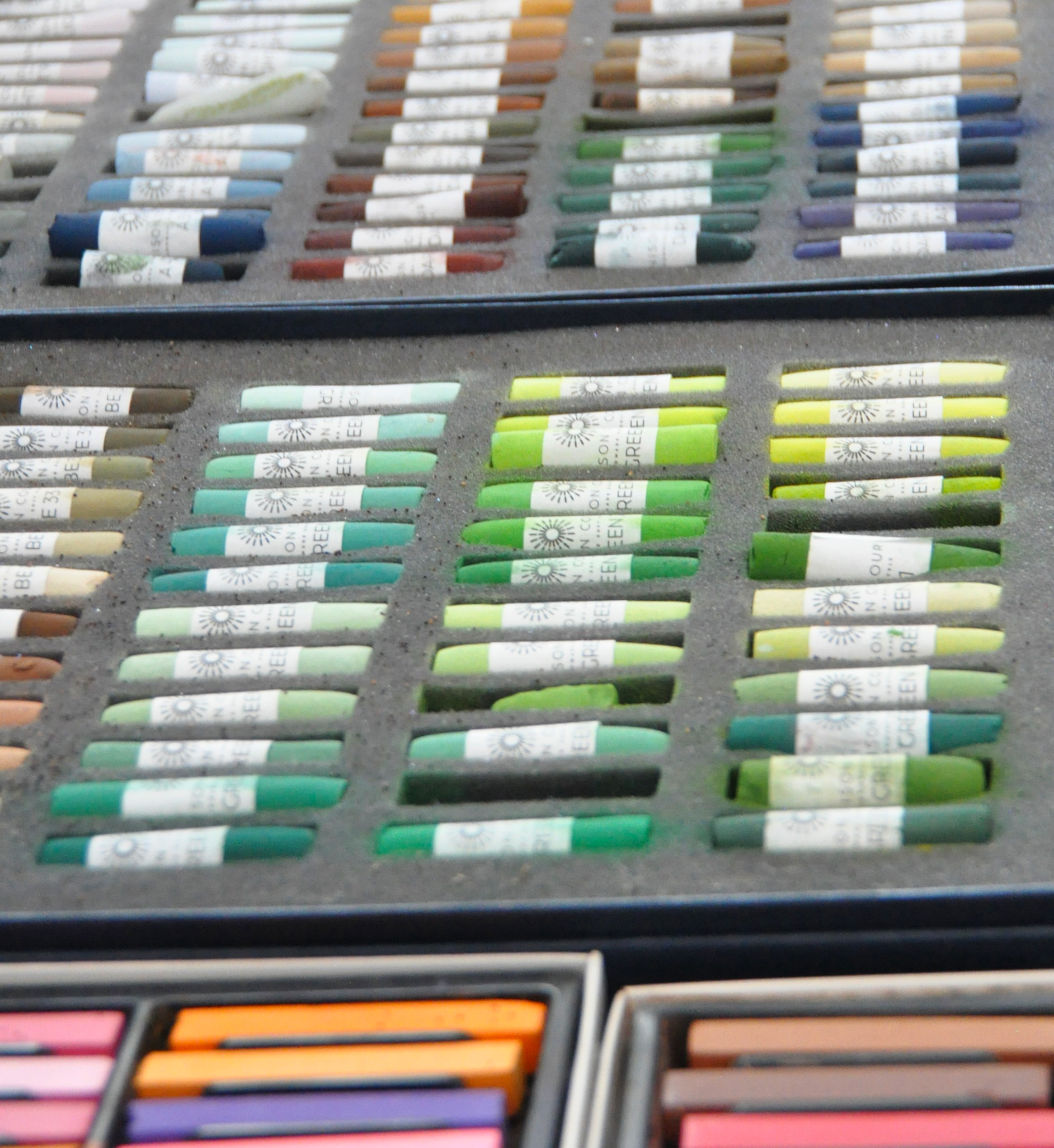 A display of pastel-colored chalks arranged in rows inside a foam-lined case.