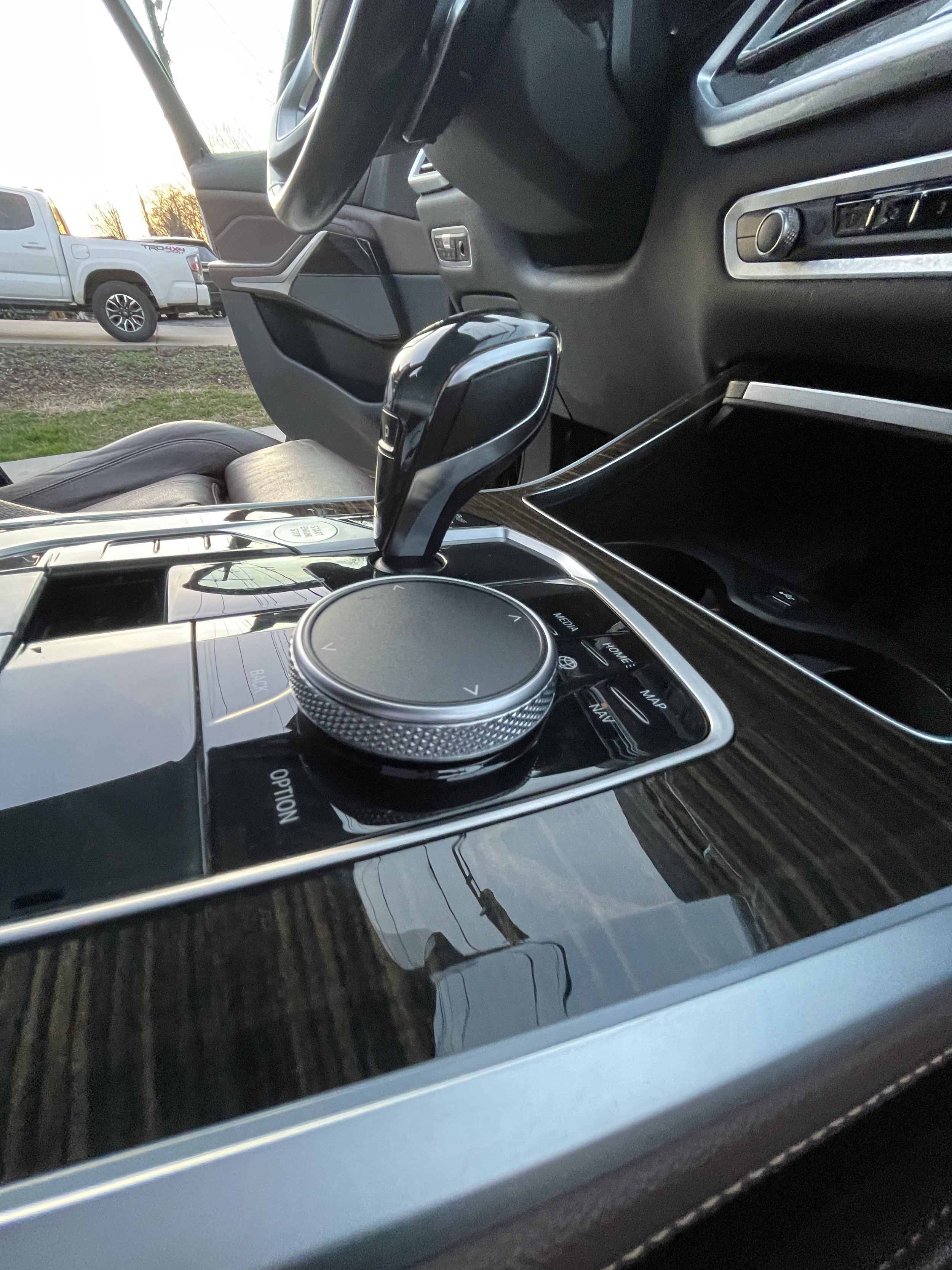 Close-up of a car's center console featuring a gear shifter and a rotary control knob surrounded by various buttons.