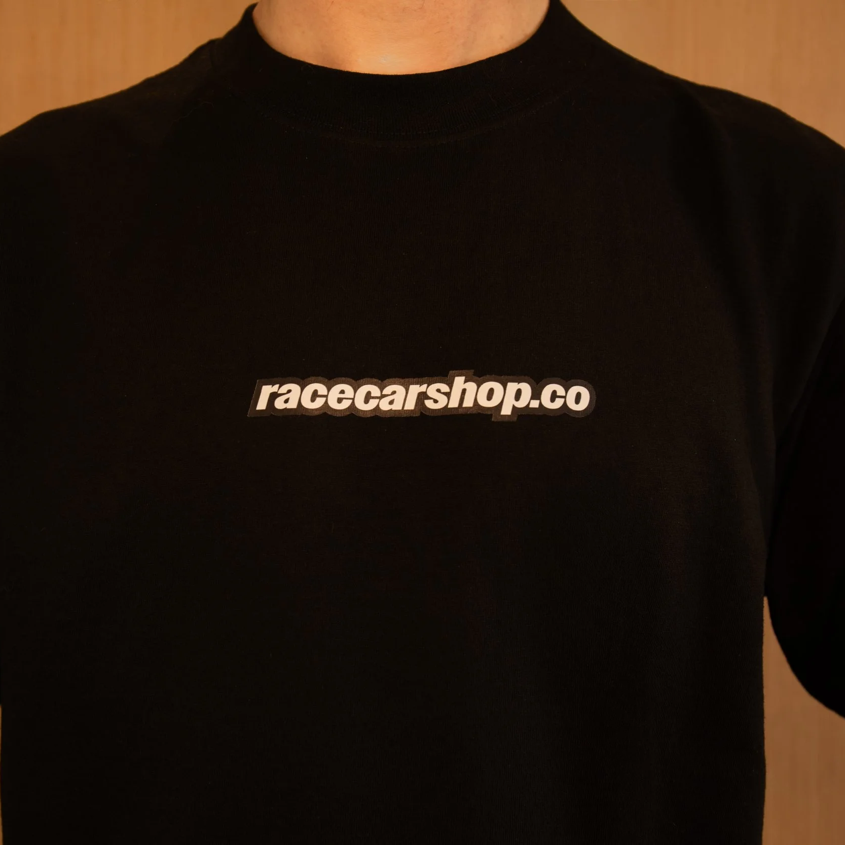 Person wearing a black shirt with the text 'racecarshop.co' printed on the front.