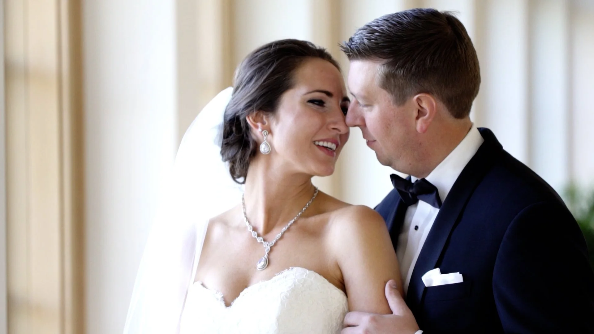 A bride and groom close together, smiling, with foreheads touching, during their wedding.