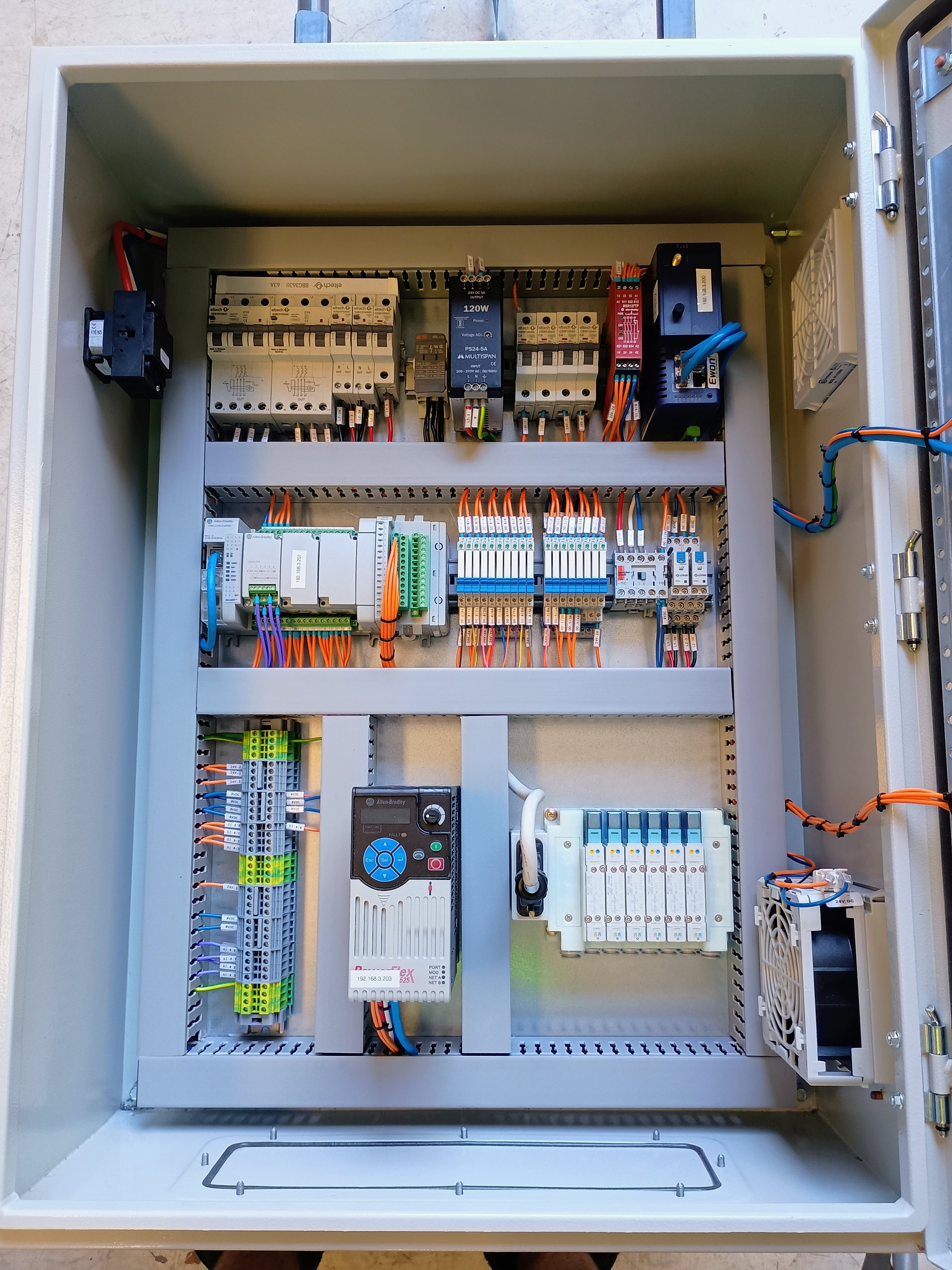 An electrical control panel with various circuit breakers, relays, terminals, and wiring inside a metal enclosure.