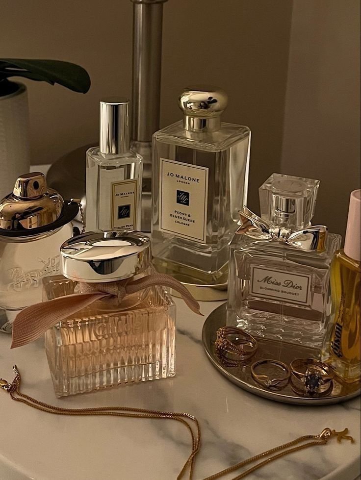 A collection of perfume bottles, rings, and jewelry on a marble surface.