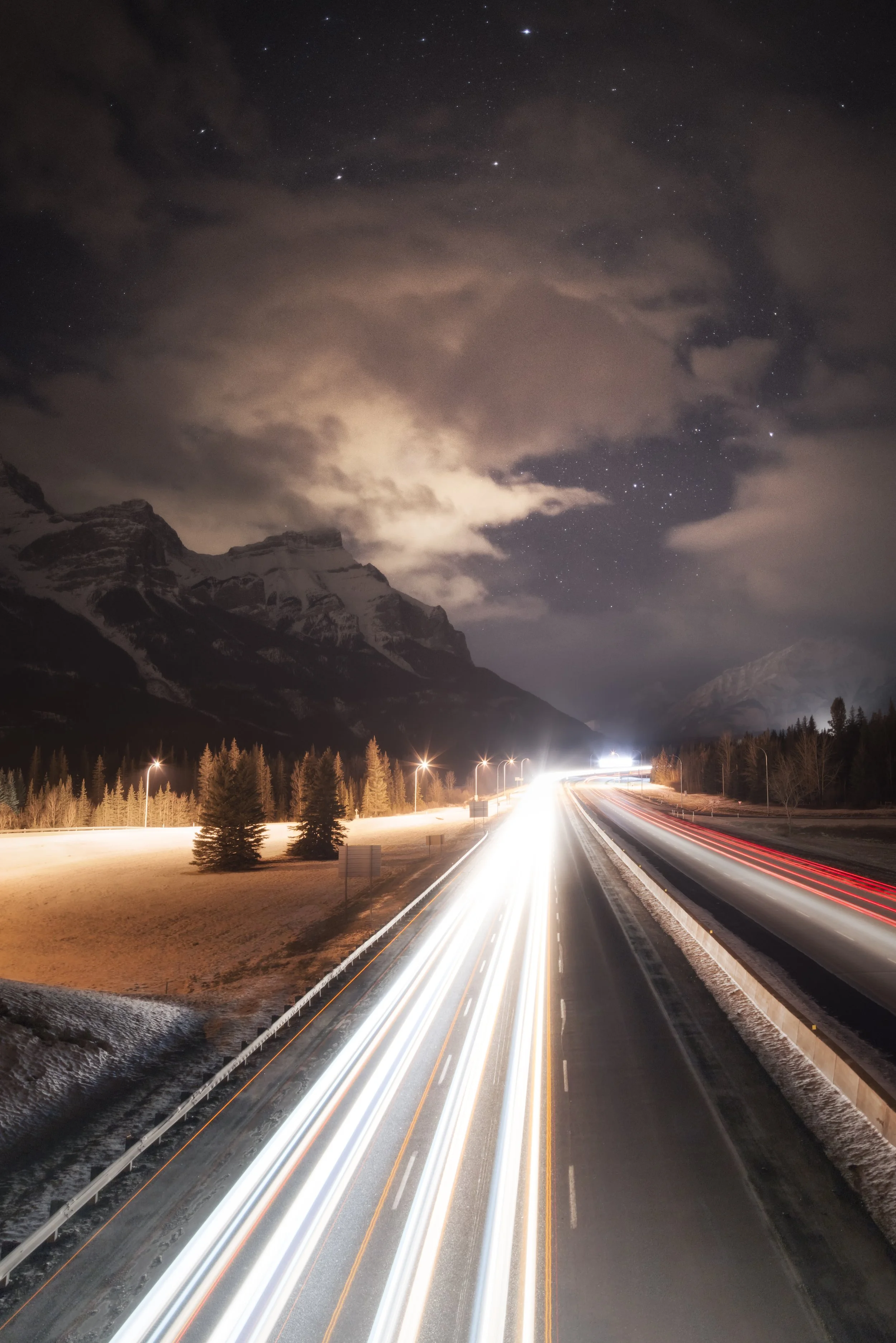 Nighttime mountain landscape with highway light trails.