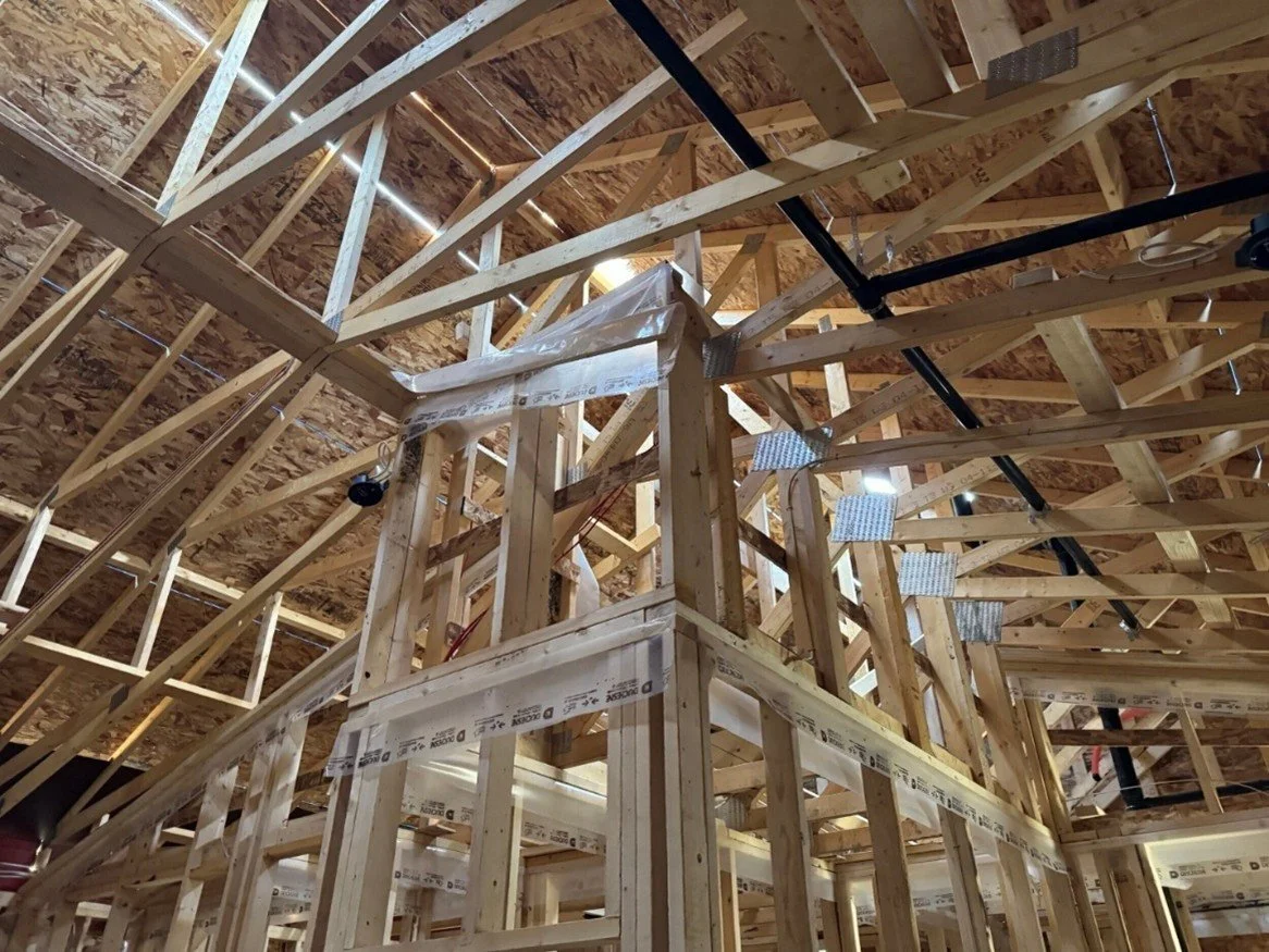 Wood framing inside a house under construction, showing beams and structural supports.