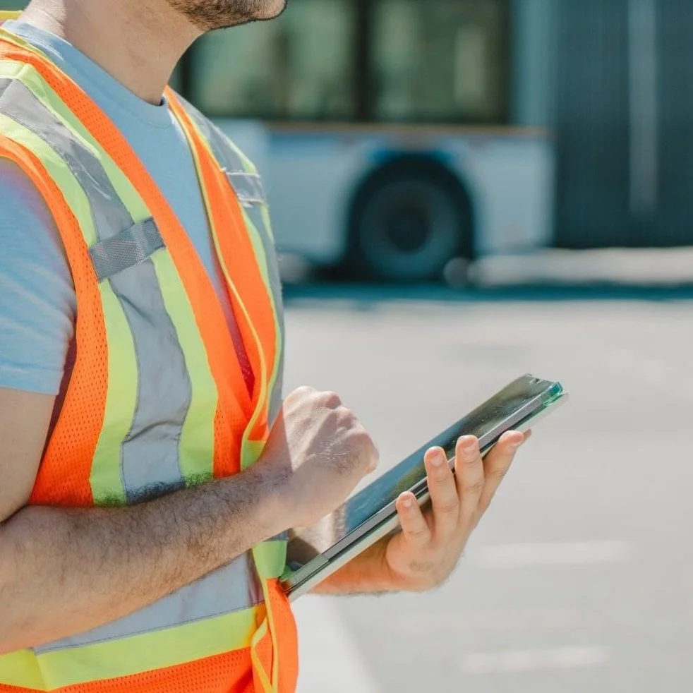 Aurora Project Solutions team member in a safety vest using a tablet to document and assess project conditions.
