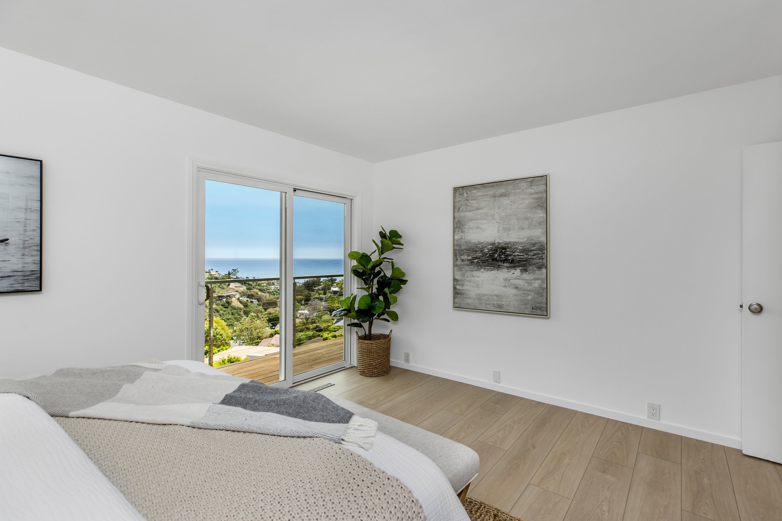 Ocean view guest bedroom with sliding glass doors leading to an ocean view terrace
