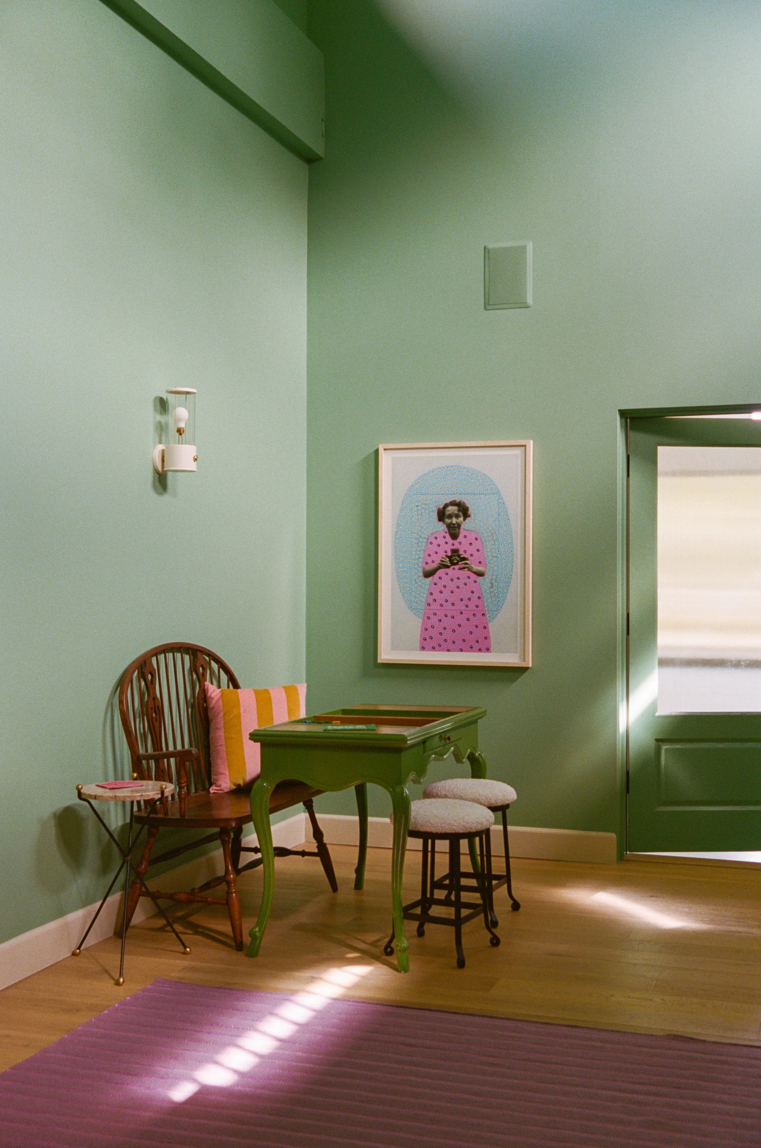 A bold color painted floor to (very high) ceiling turns a stairwell area into a comfortable place to hang out, with art, antiques and layers of colors and textures.