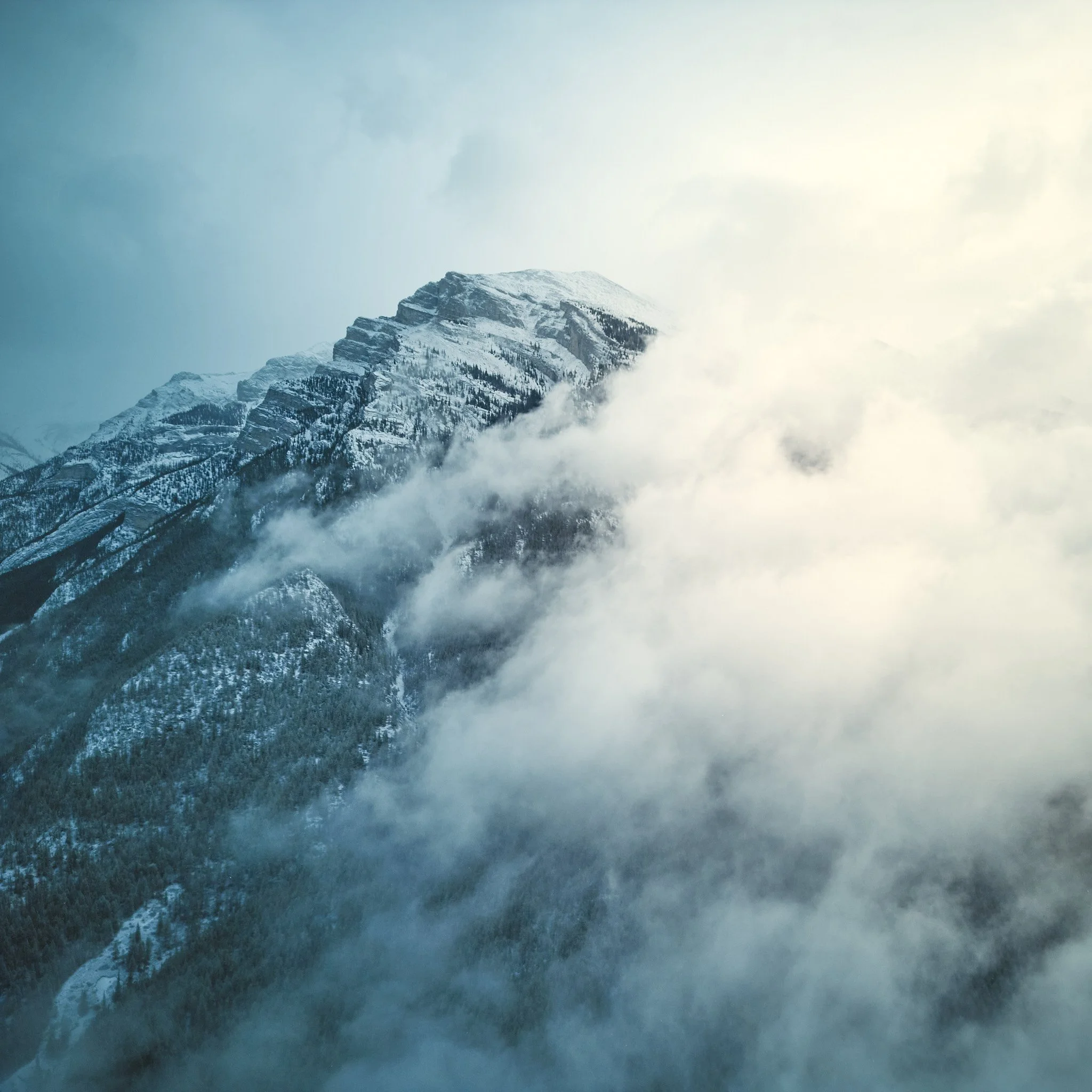 Snow-capped mountain peak surrounded by clouds and mist