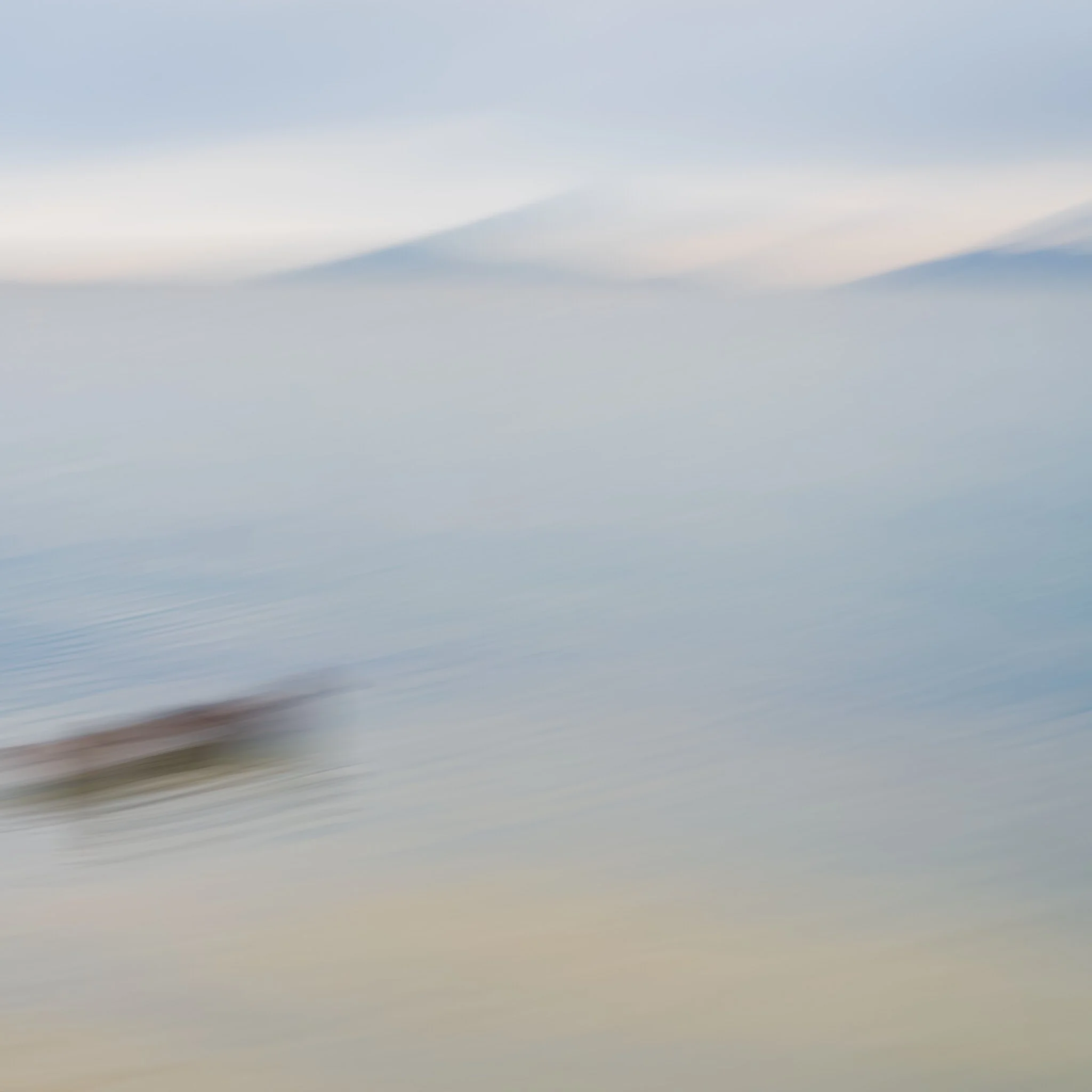 A blurry image of a boat on calm water with mountains in the background