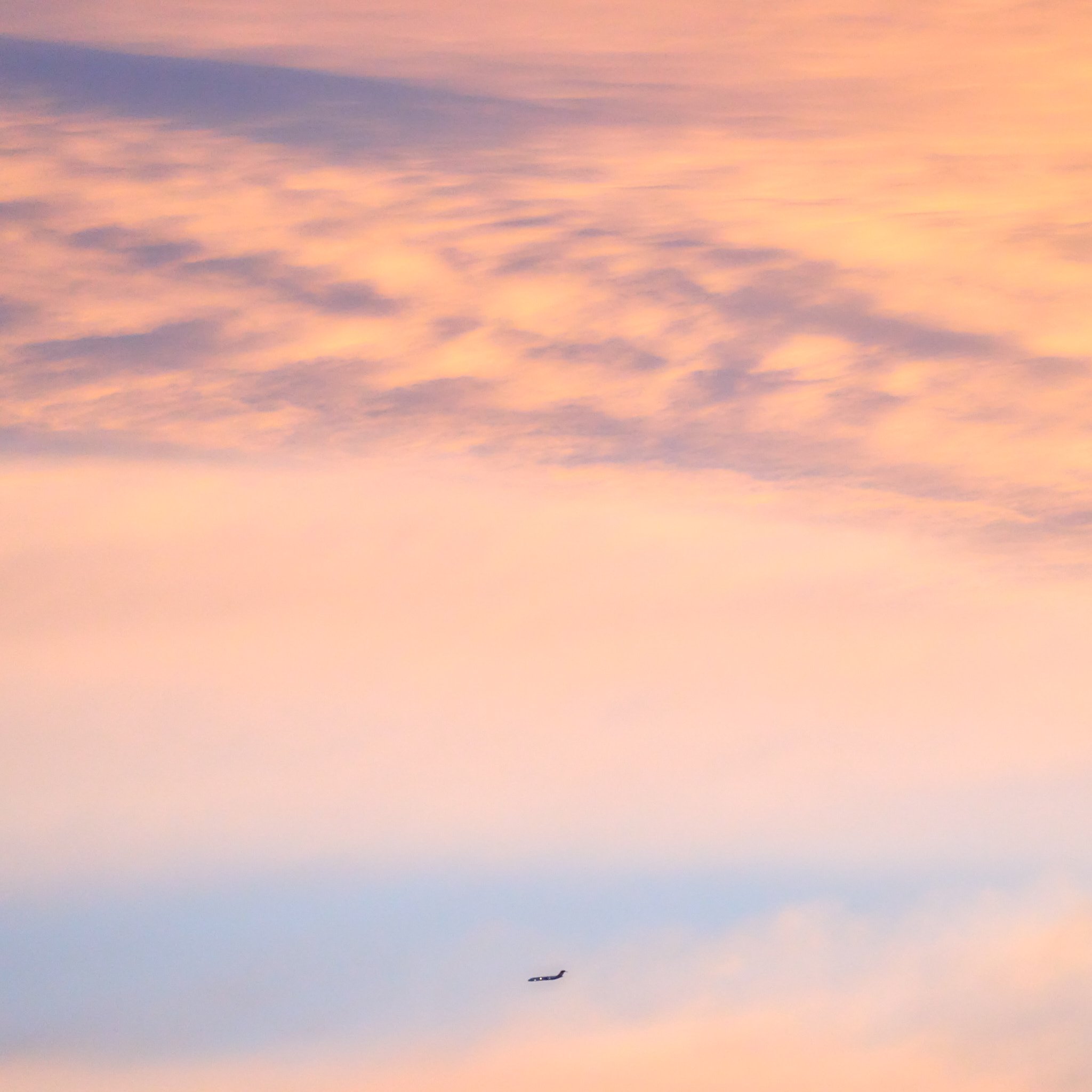 A colorful sky during sunset with pink, purple, and blue clouds. A single airplane is visible near the bottom of the image. Victoria Australia