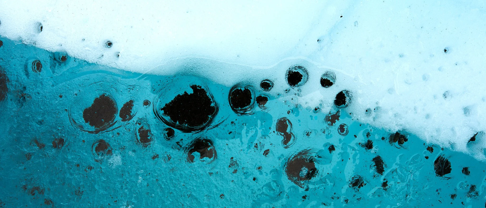 Close-up of bubbles and ice crystals in blue water.