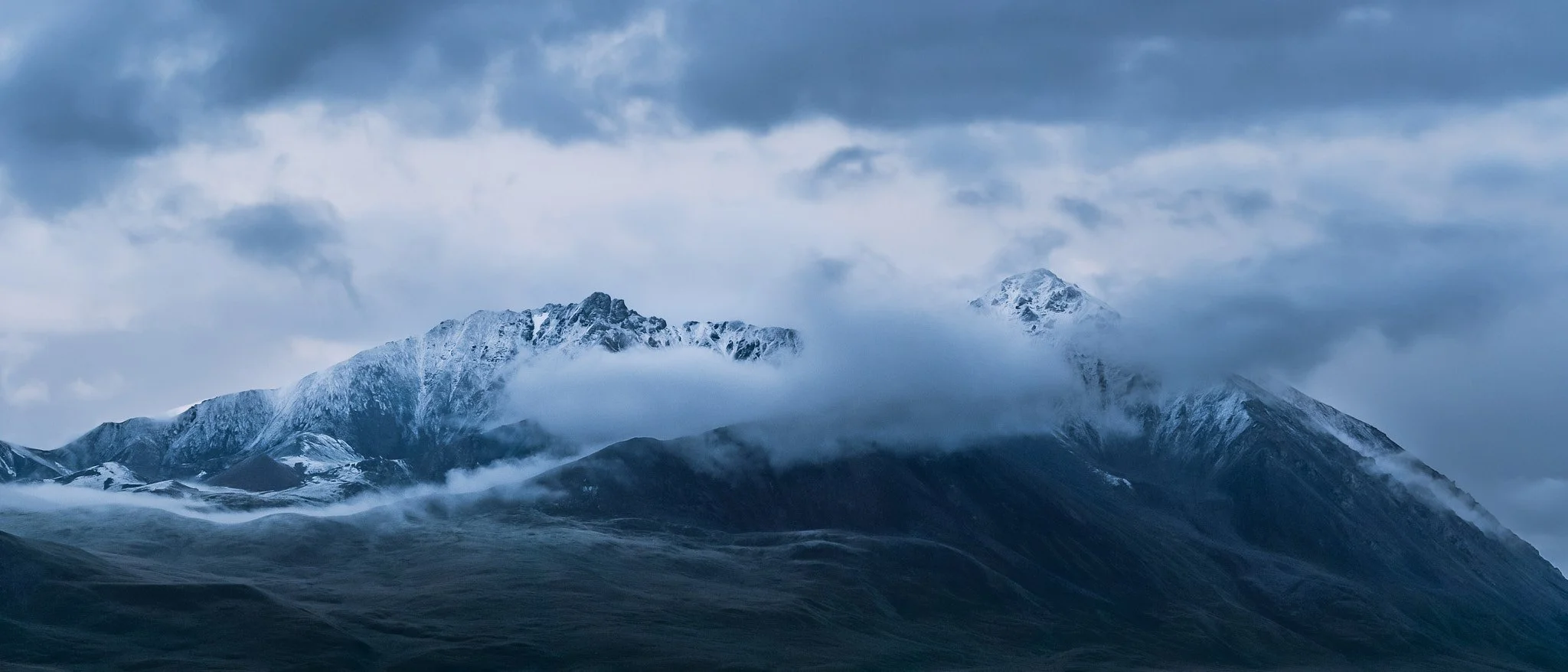 Snow-capped mountains surrounded by clouds and mist