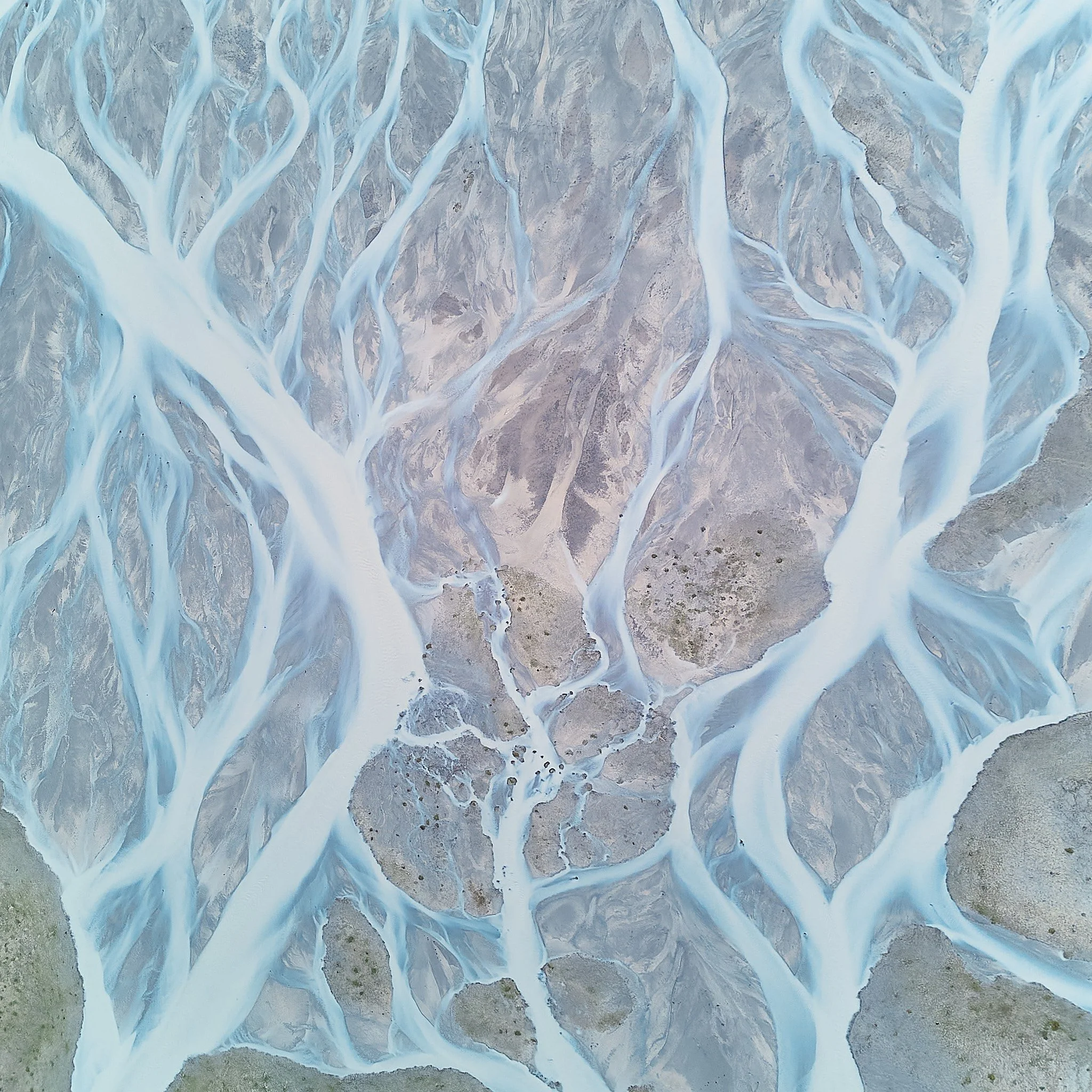 Aerial view of light blue rivers and streams flowing through a desert landscape.