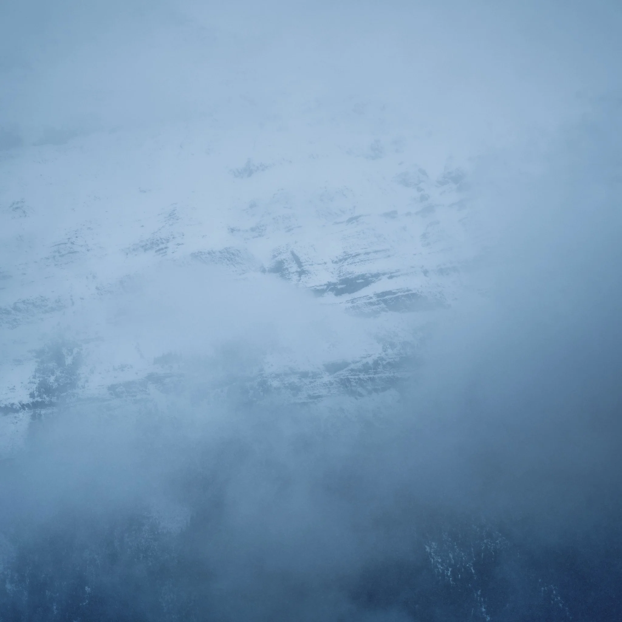 A cloudy, overcast sky with shades of blue and gray, and indistinct mountain or railing in the distance.