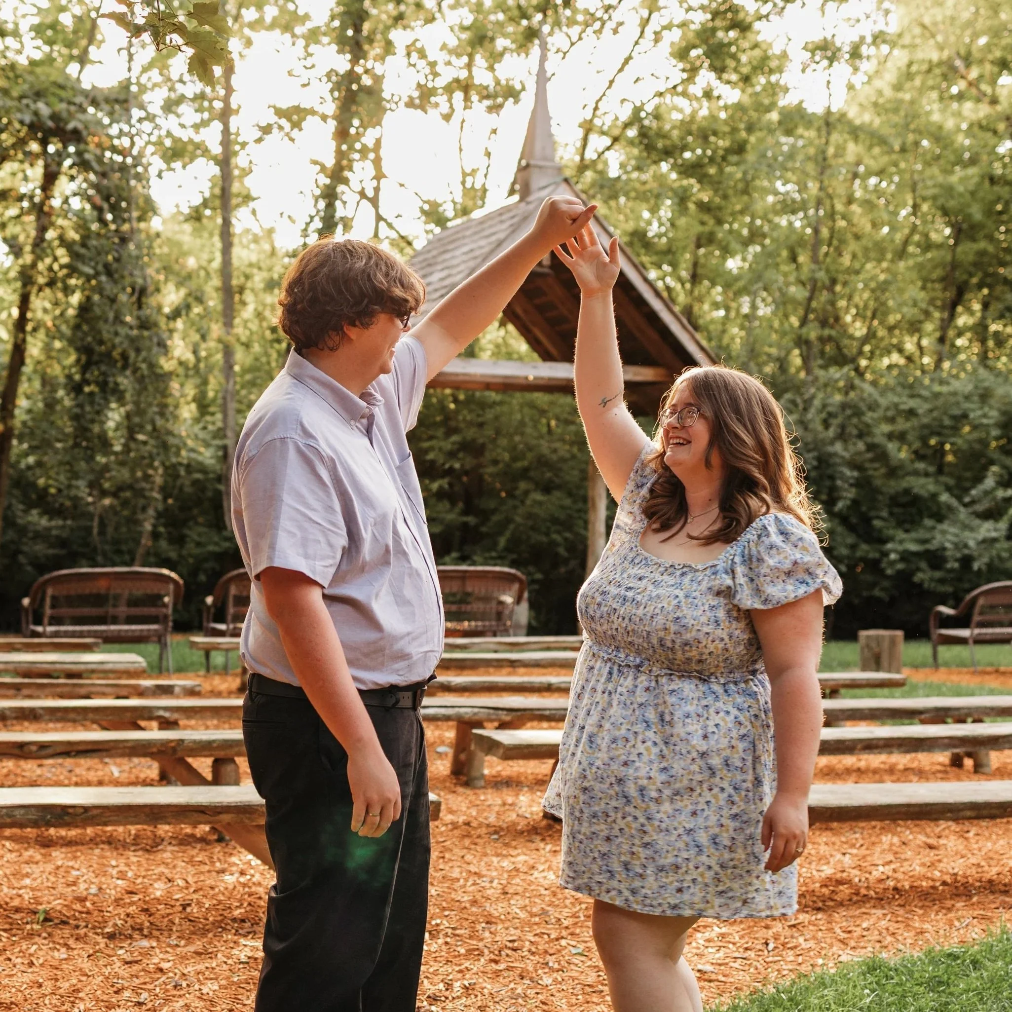couple dancing in the woods in front of a wedding chapel